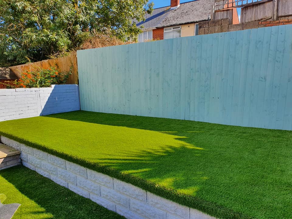 a man leaning over a wooden desk with a clock in the background