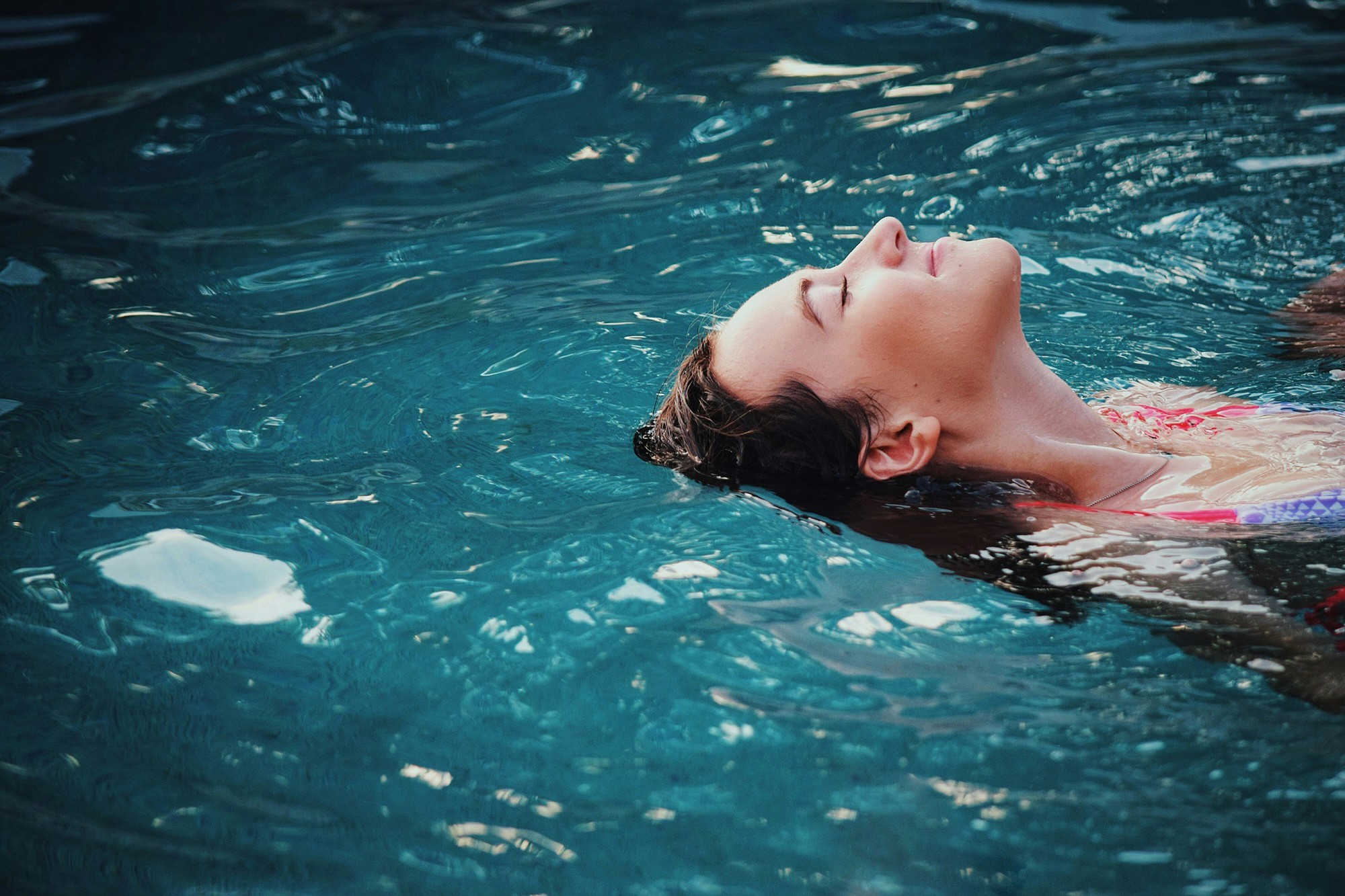 woman lying on grass front of sea at daytime