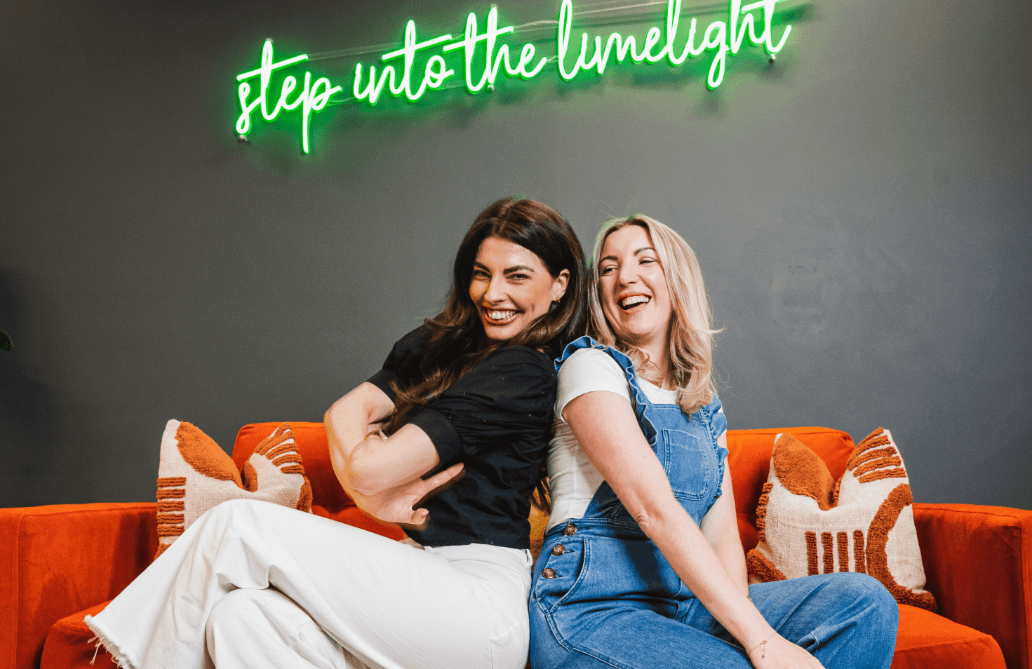 People sitting on a couch in front of an overhead sign.