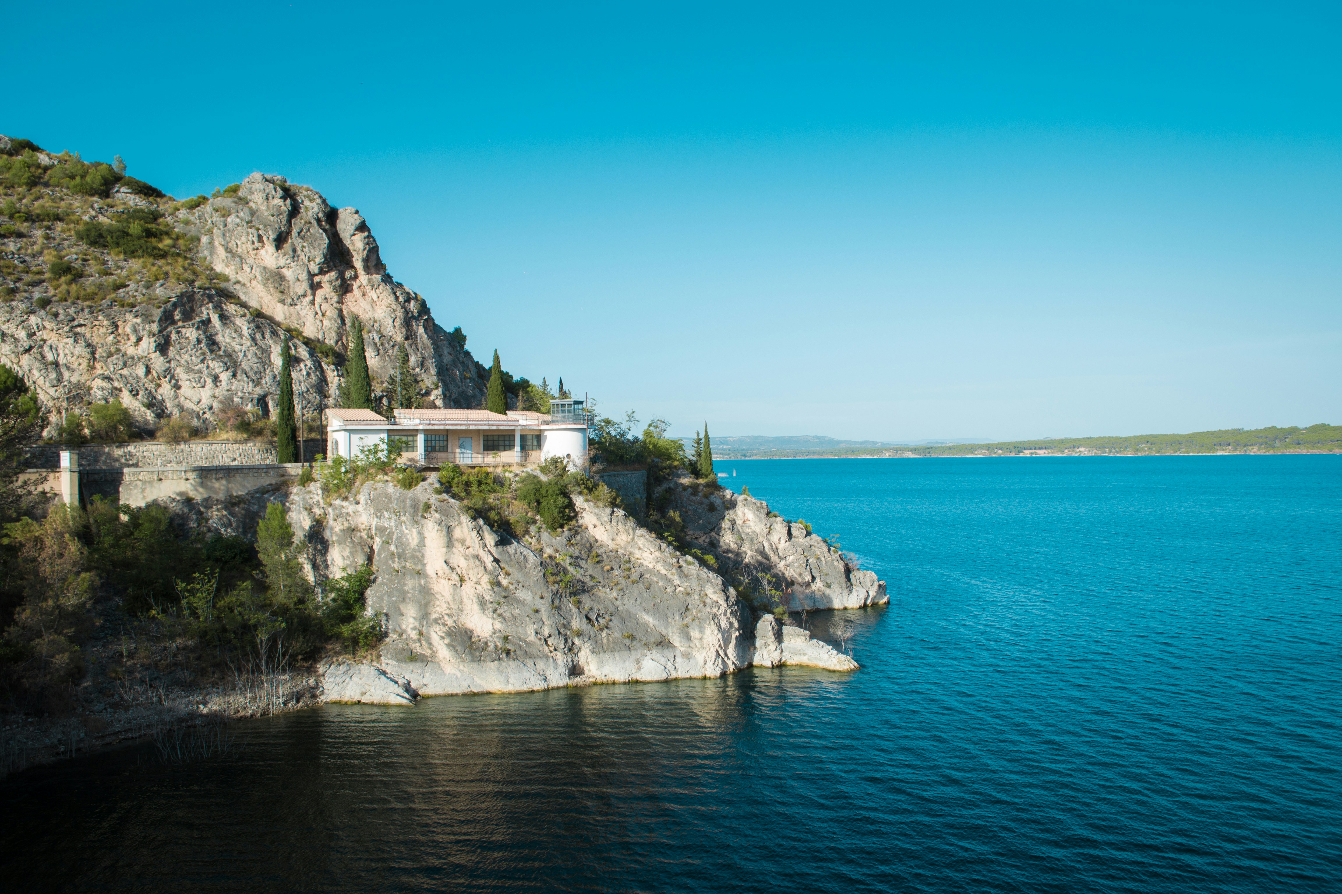 House on a cliff overlooking a large blue lake.