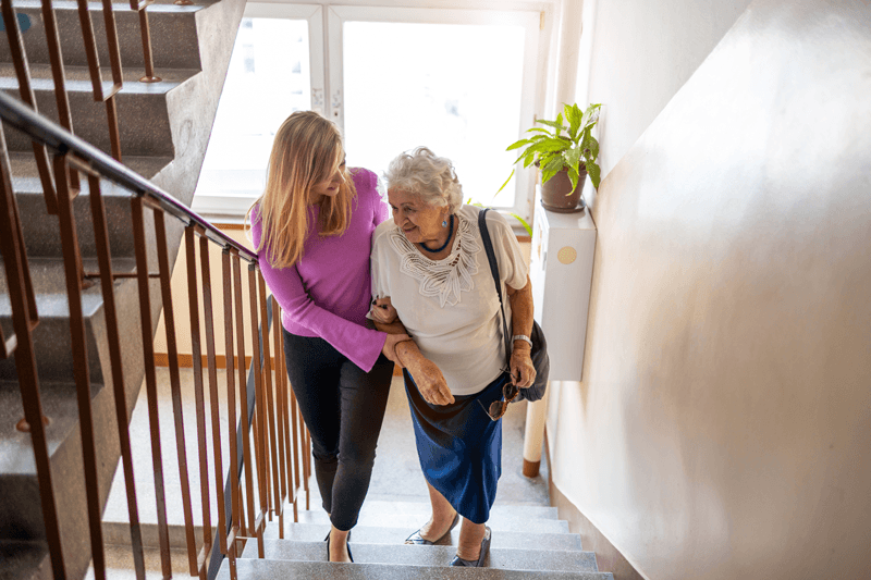 Caregiver Walking Senior Up the Stairs