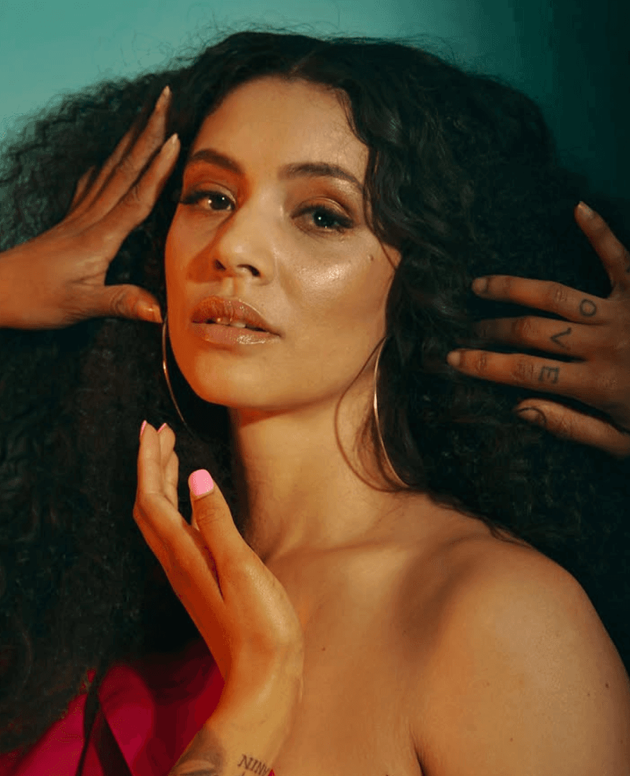 Young woman with dark hair and bangs, wearing red.