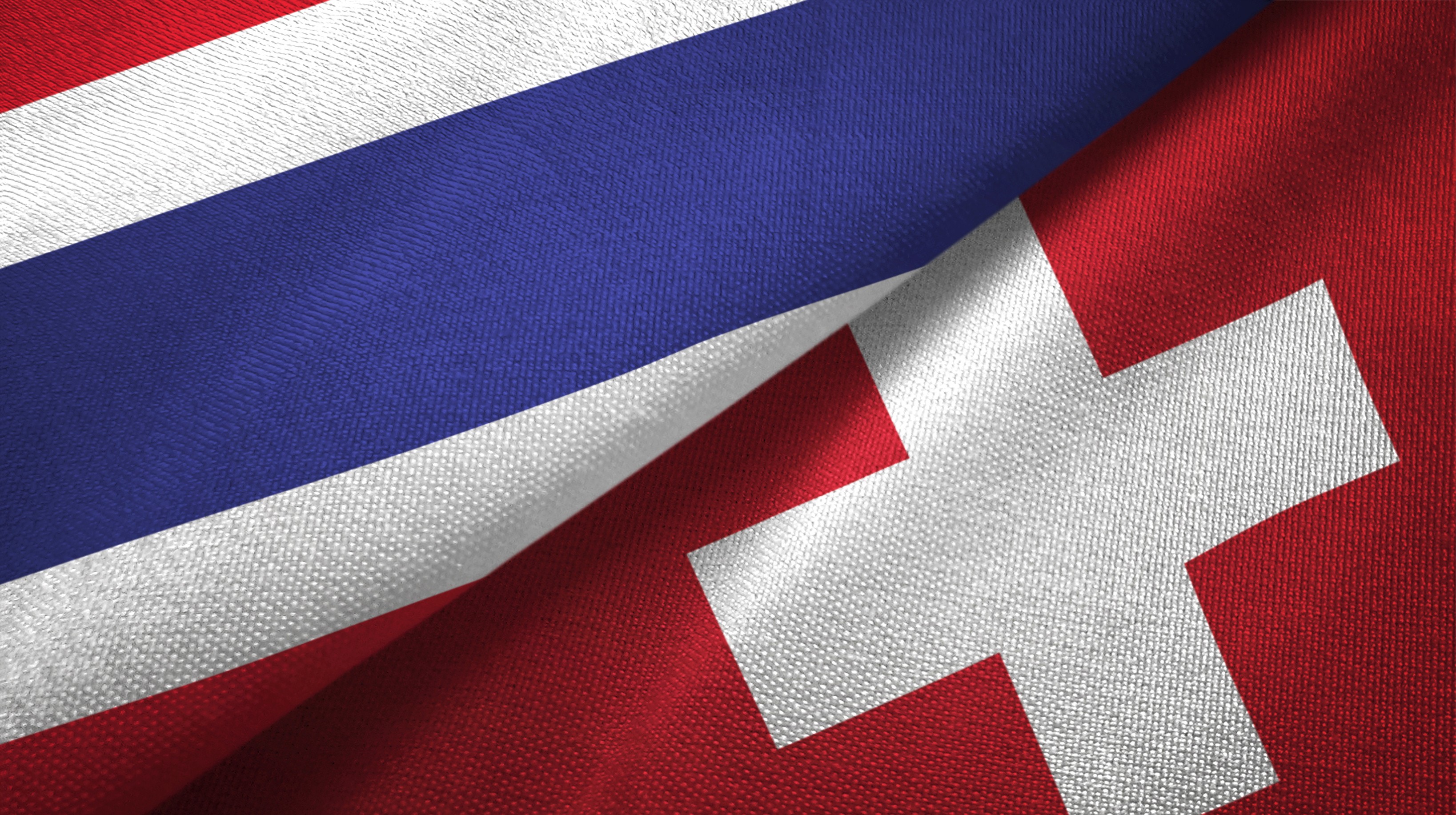 Close-up of the Thai and Swiss flags overlapping, symbolising trade relations between Thailand and Switzerland.