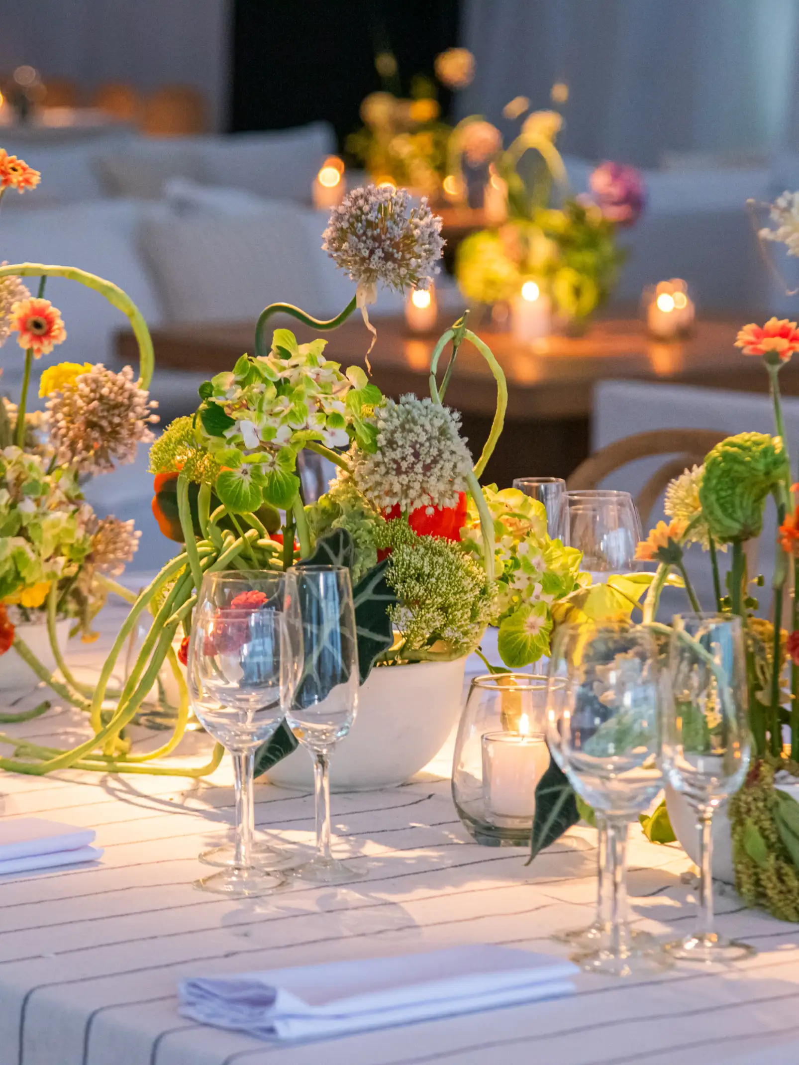 Mesa decorada con arreglos florales coloridos y velas encendidas, creando una atmósfera cálida y elegante.