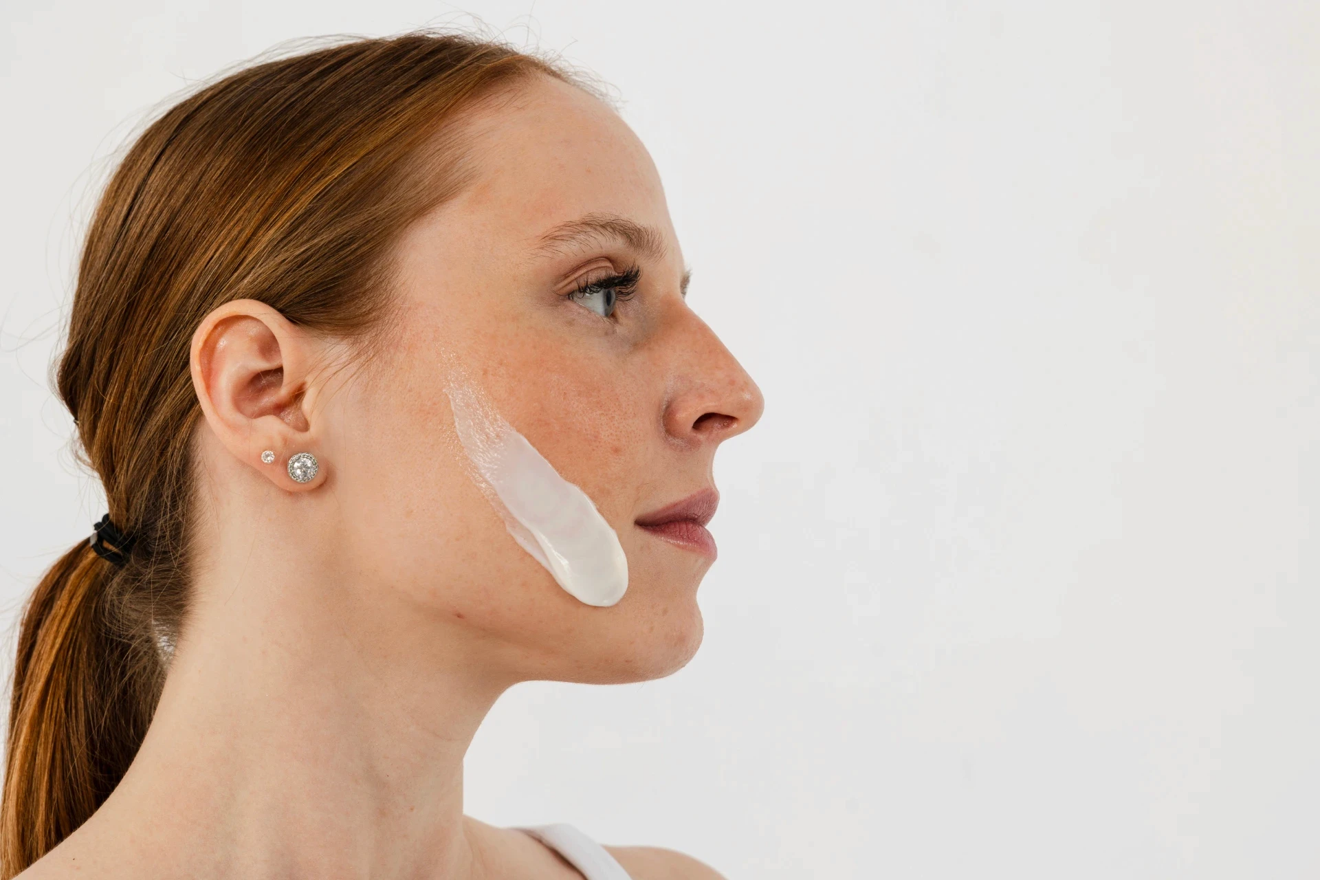Woman with cream on cheek. Visual identity designer Barcelona for beauty brands.