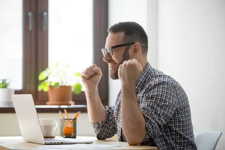 happy and successful man sitting in front of a computer