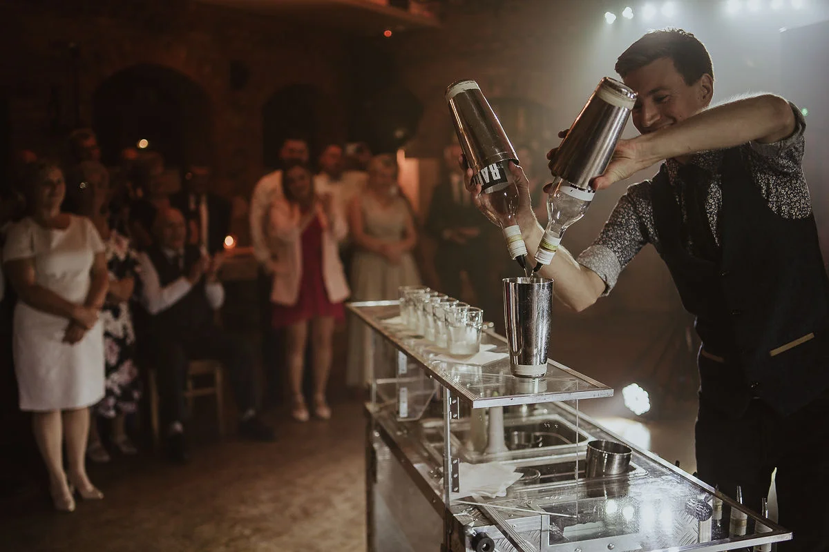 Drink bar na weselu z barmanem zachwycającym gości podczas pokazu.