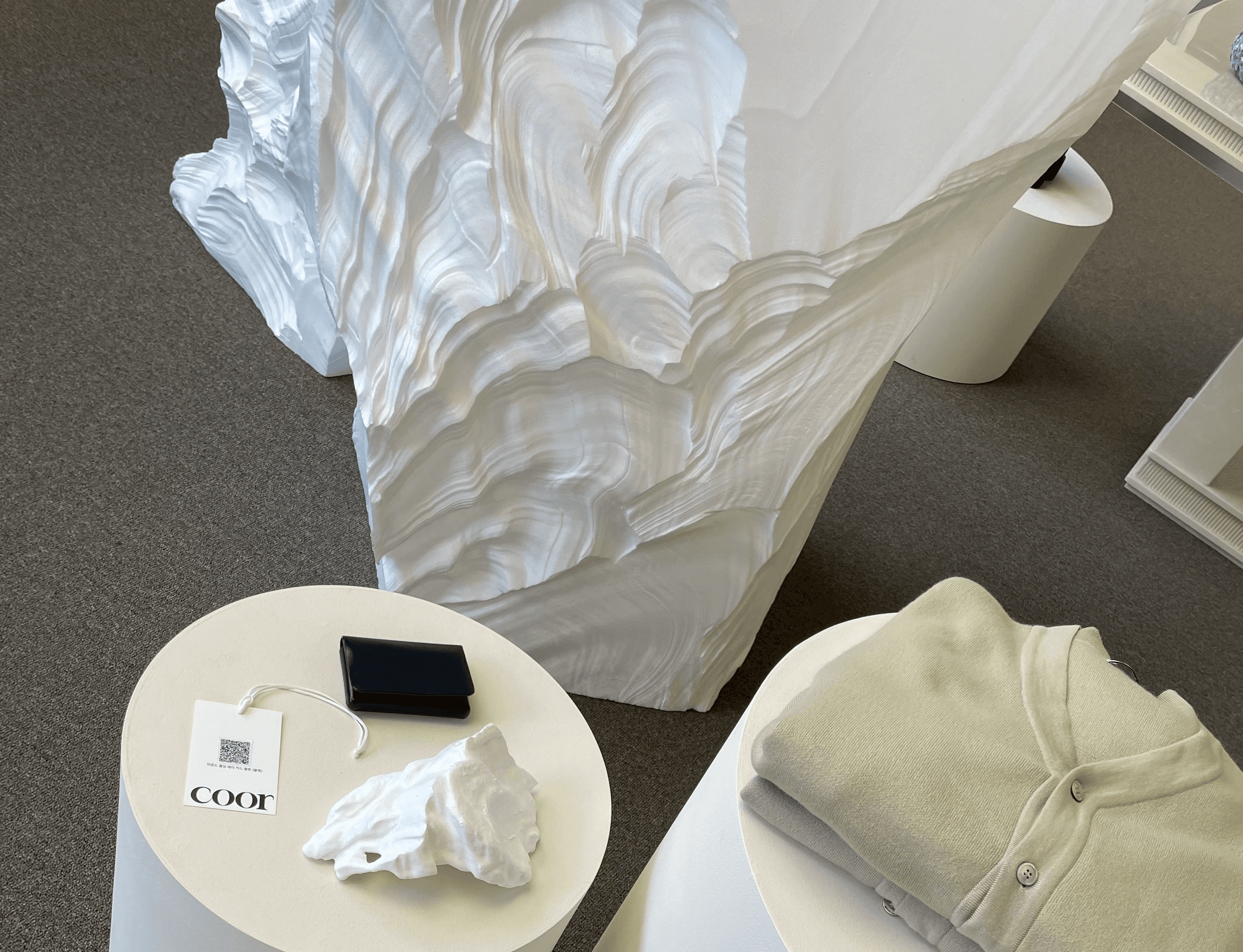 쿠어 팝업 VMD 디테일, 의류 디스플레이와 조형 오브제 배치, 브랜드 태그 / COOR pop-up VMD detail, apparel display with sculptural objects, brand tag