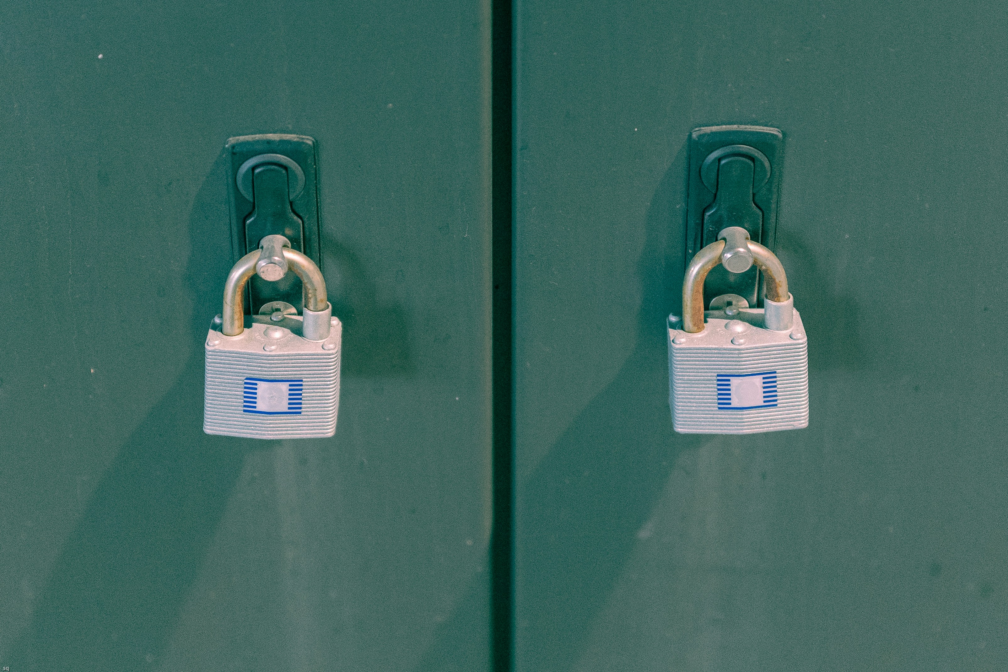 two green lockers with padlocks on them