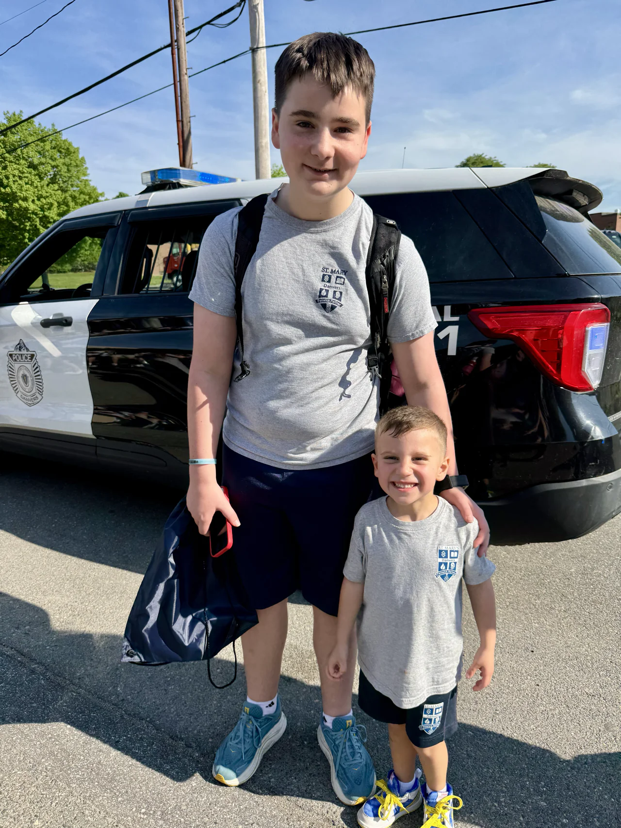 Two students posing in front of a Danvers police vehicle