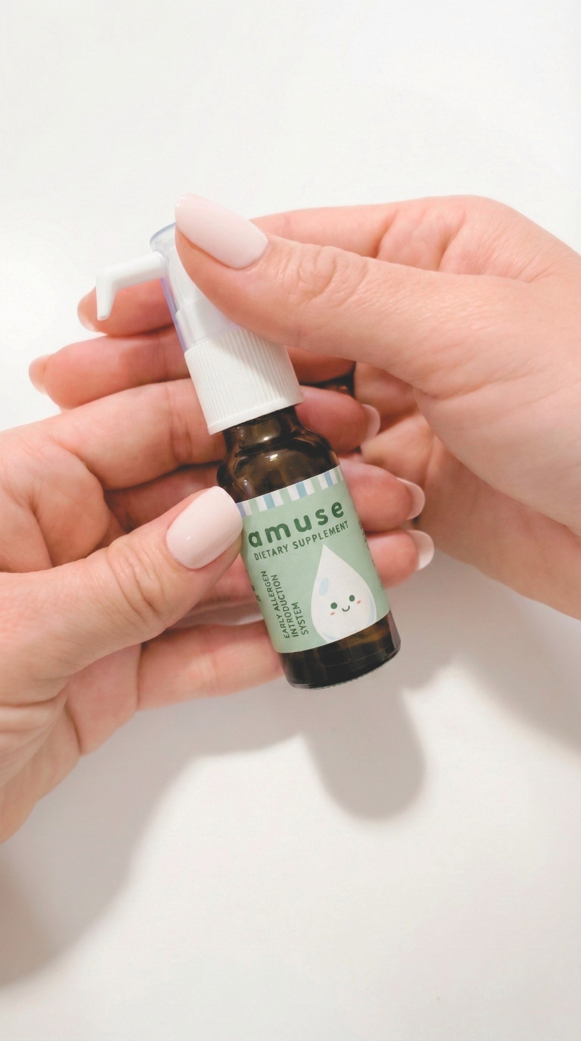 Hands holding an Amuse Drops bottle with a daily-use pump dispenser.