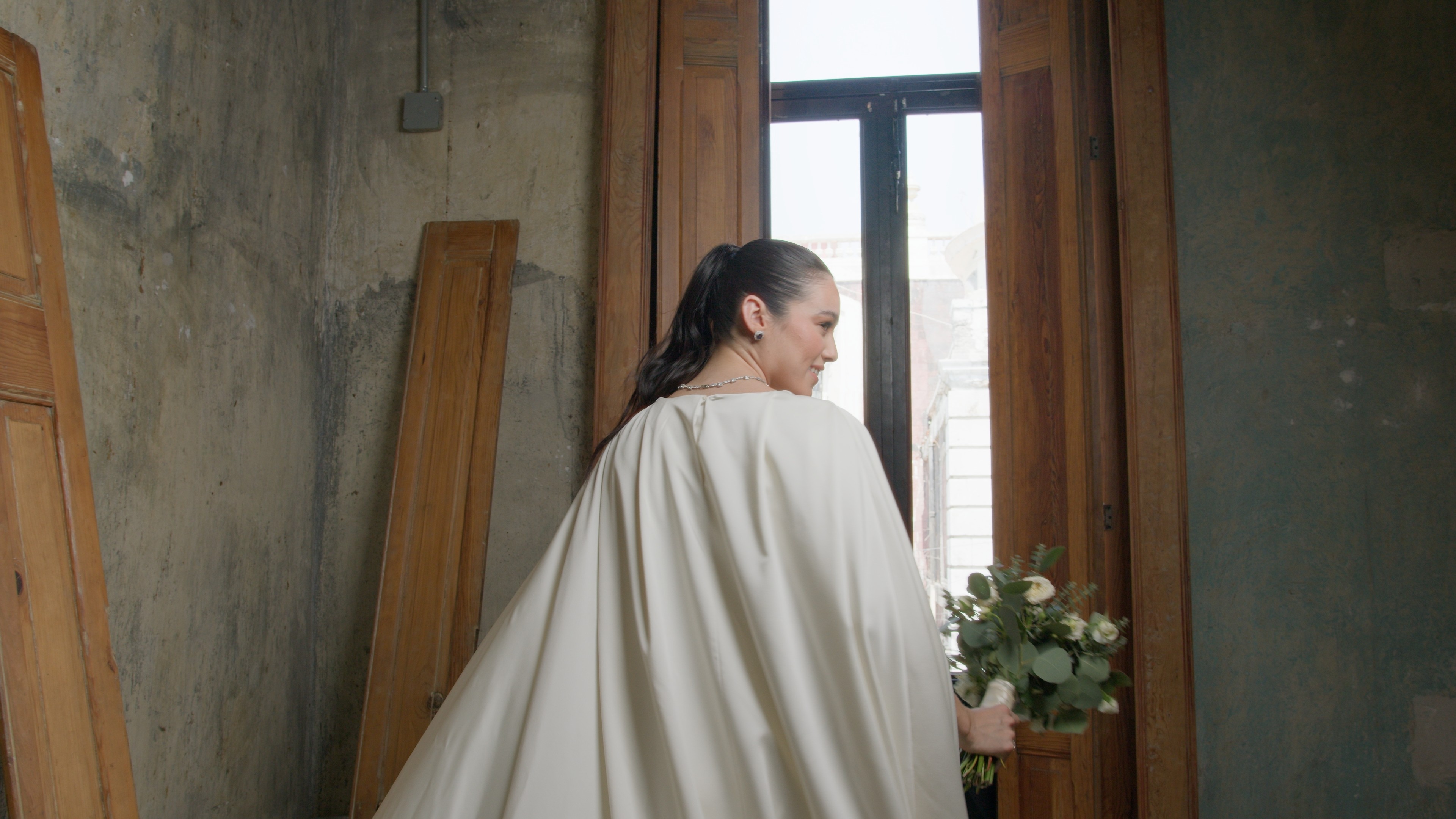 Cinematic still from the 'Resilencia Nupcial' fashion film featuring model Angela Carrillo in a Paulina Ramos bridal design. Photographed by Mexico City DP Mauricio Nader using soft natural light at the iconic Dolores 54 building in the Centro Histórico.