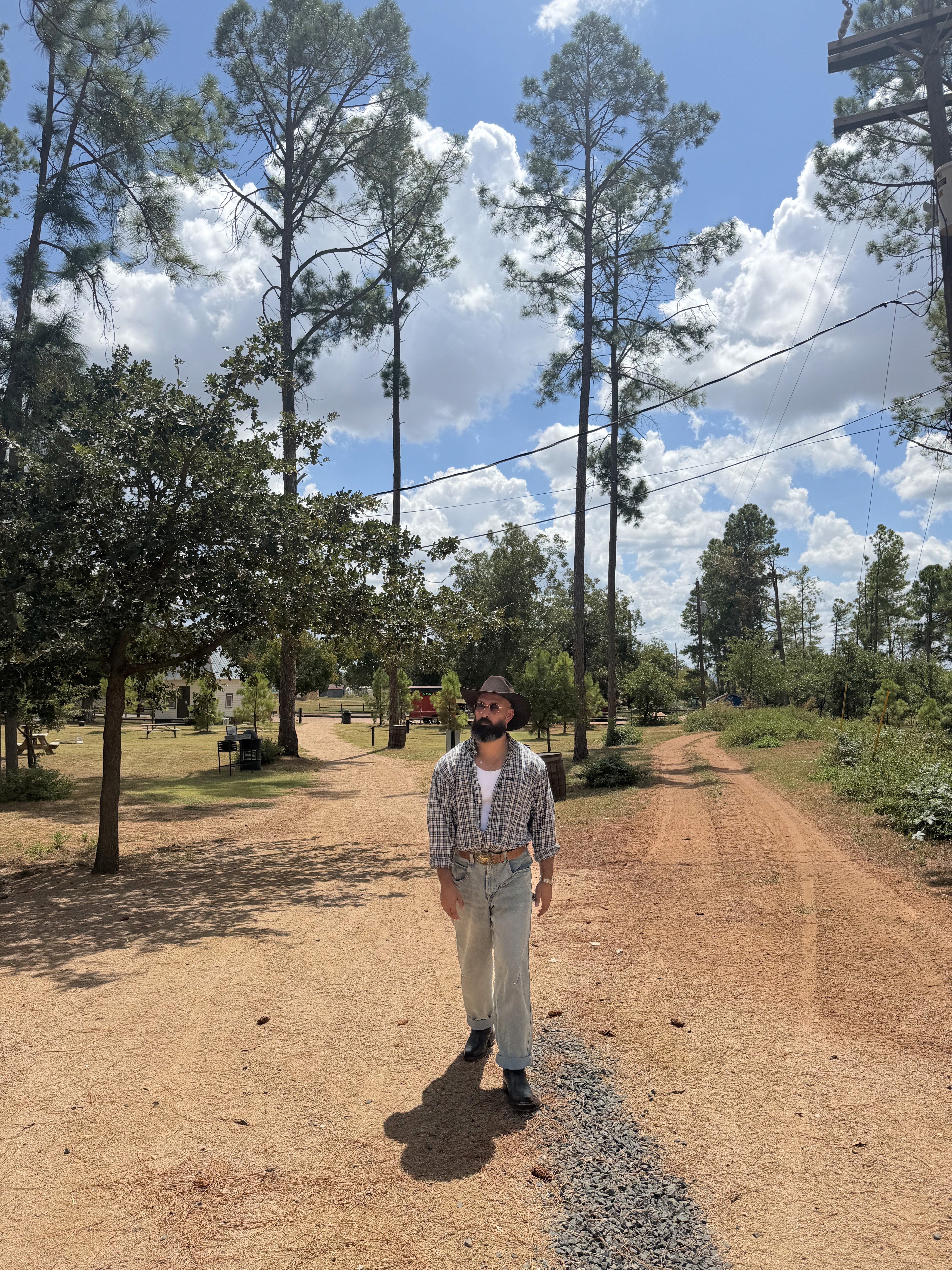 Jamie Lyons walking along a dirt path lined with tall pine trees
