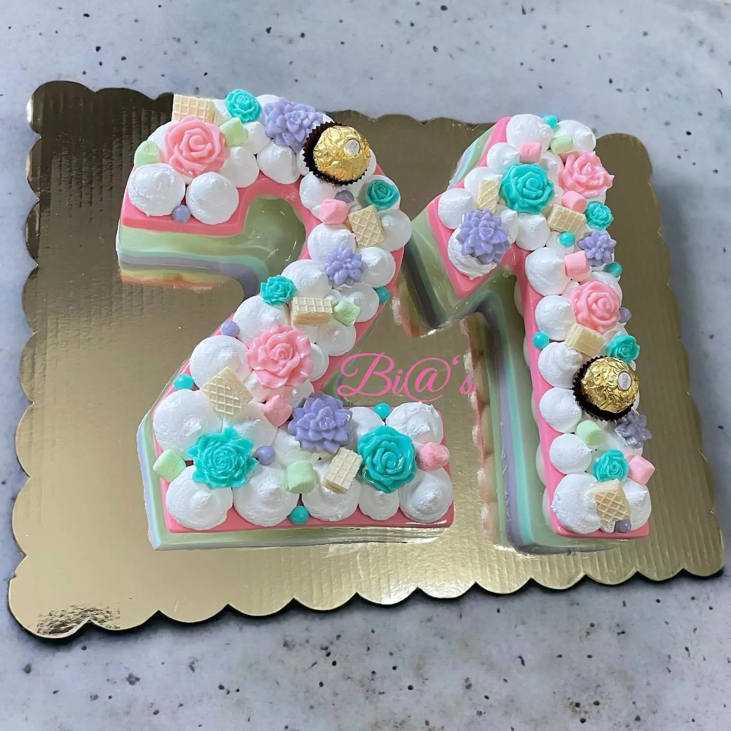 Number-shaped gelatin cake in “21” filled with pastel-colored floral designs and candy embellishments. A creative treat that makes a statement at any celebration. Susa’s Sweets & Balloons.