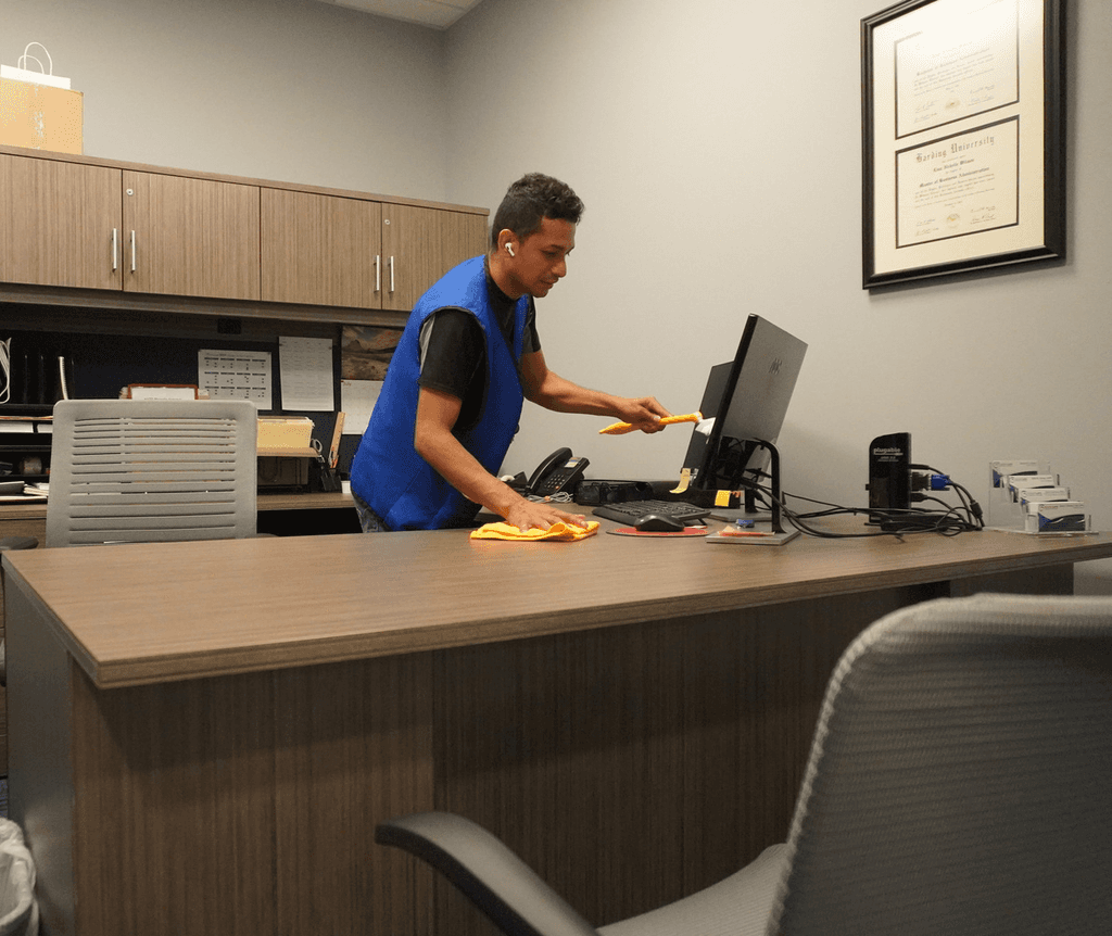 Office cleaning service wiping down desk