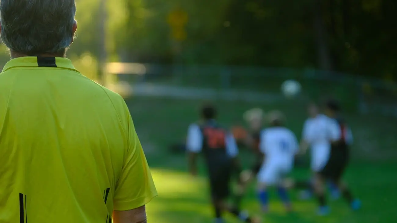 A referee monitors a football match, equipped with an innovative RefCam to capture the referee's perspective during a Bundesliga match. This technological development provides unique insights and promotes transparency in refereeing decisions.