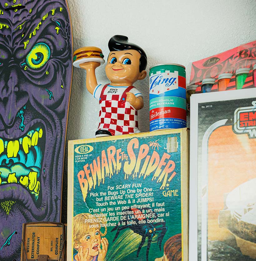 Shelf display featuring a Bob's Big Boy figurine holding a burger beside a vintage Zing soda can and a “Beware the Spider” game box, with a Rob Roskopp face skateboard in the background.