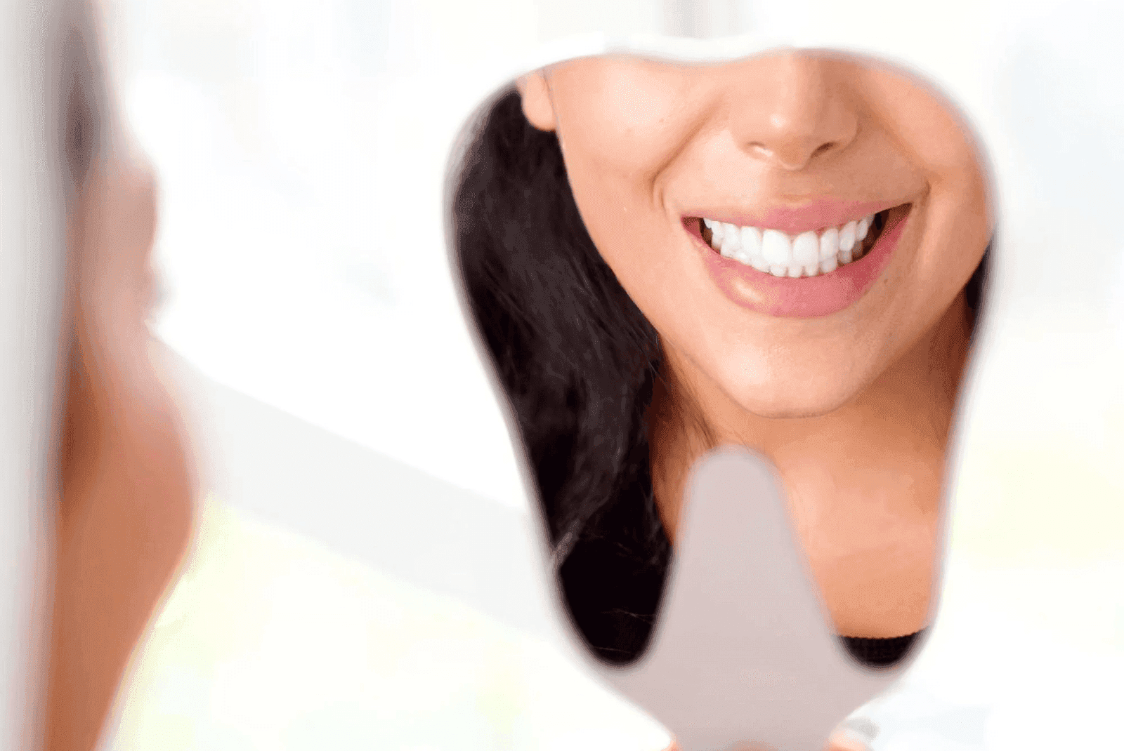 إحدى عميلات مركز إنفزلاين تتأمل ابتسامتها في المرآة بعد تركيب تيجان الأسنان والتى أبرزت جمال ولمعان ابتسامتها بما يتلائم مع طبيعة أسنانها.