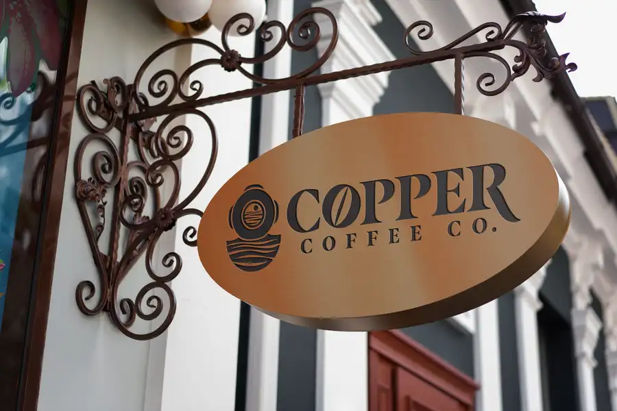 Copper Coffee Co. oval sign mockup hanging outside a storefront