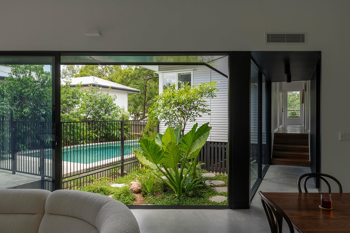 Interior living space of Toohey Forest House with sliding glass doors opening to landscaped courtyard and pool.