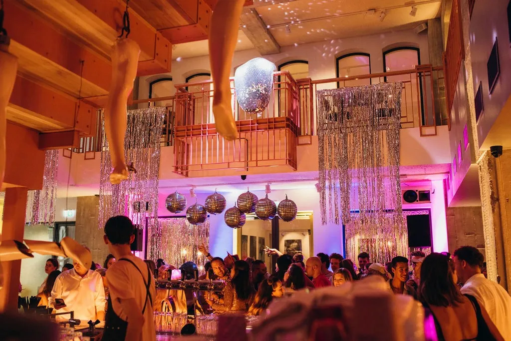 A lively event in a beautifully decorated venue with colorful lights and an audience enjoying the performance.