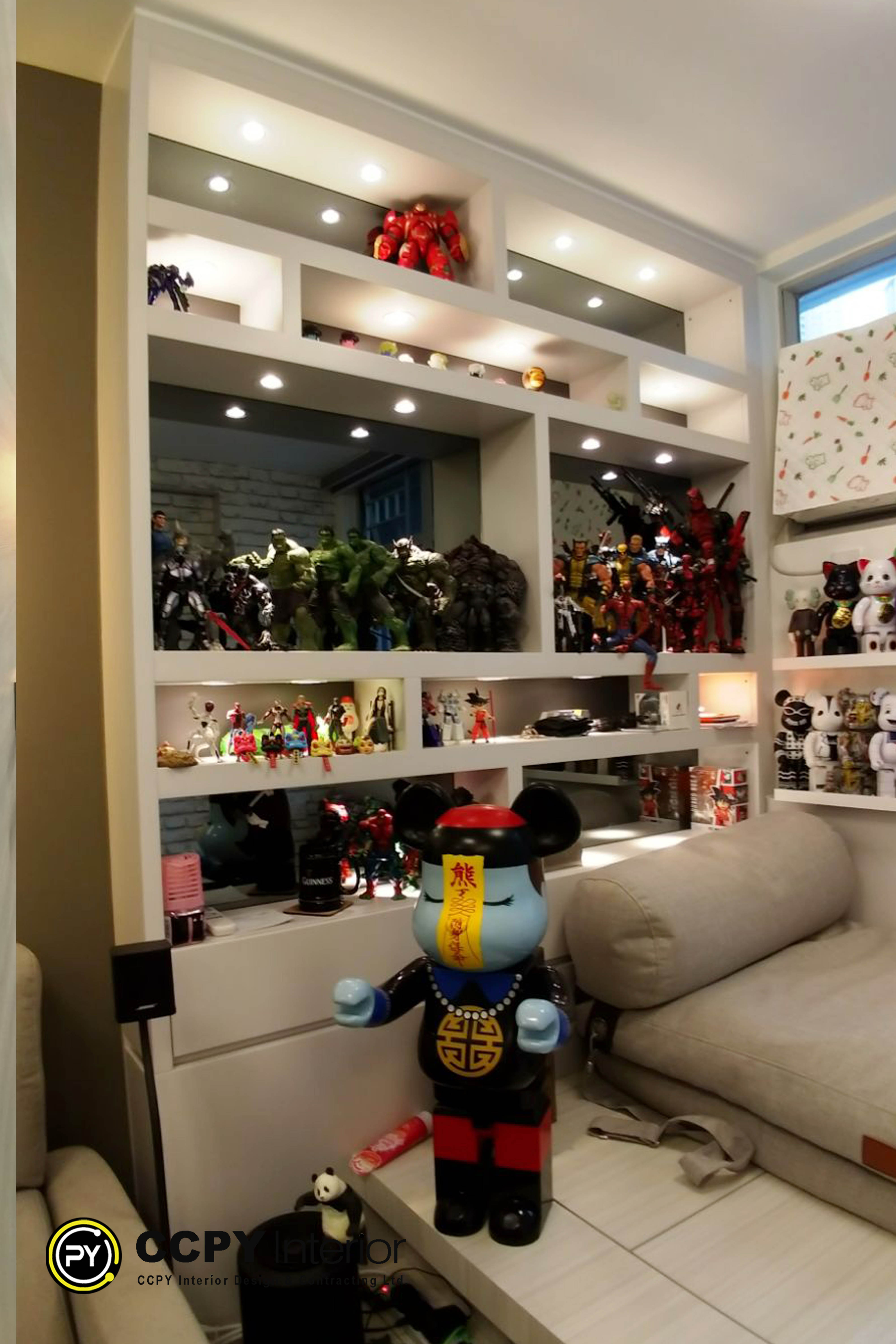 This comprehensive renovation project features a vibrant, family-oriented apartment design tailored for displaying extensive toy collections.Here is a breakdown of the key elements seen in this home design:Open Display CabinetryCustom Shelving: Recessed, multi-tier shelving units built directly into the wall structure maximize vertical space.Integrated Lighting: Built-in spotlights and LED strip lighting illuminate each shelf to highlight the collectibles.Varying Compartments: Square and rectangular cubbies of different sizes accommodate figurines of diverse scales.Focused Collectible ThemesSuperhero Shelf: The prominent top shelf showcases large-scale action figures, heavily featuring Marvel characters like the Hulk, Iron Man, and Captain America.Pop Culture Icons: Lower shelves display recognizable characters, including Bearbrick figures and various Japanese anime figurines.Sanrio Touches: Subtle Hello Kitty themed items add a playful, soft contrast to the action-oriented collectibles.Complementary Interior ElementsNeutral Backdrop: Light-colored walls and warm wooden textures prevent the densely packed shelves from overwhelming the room.Cozy Seating: A plush neutral sofa is positioned directly adjacent to the display, creating a comfortable viewing and gathering area.