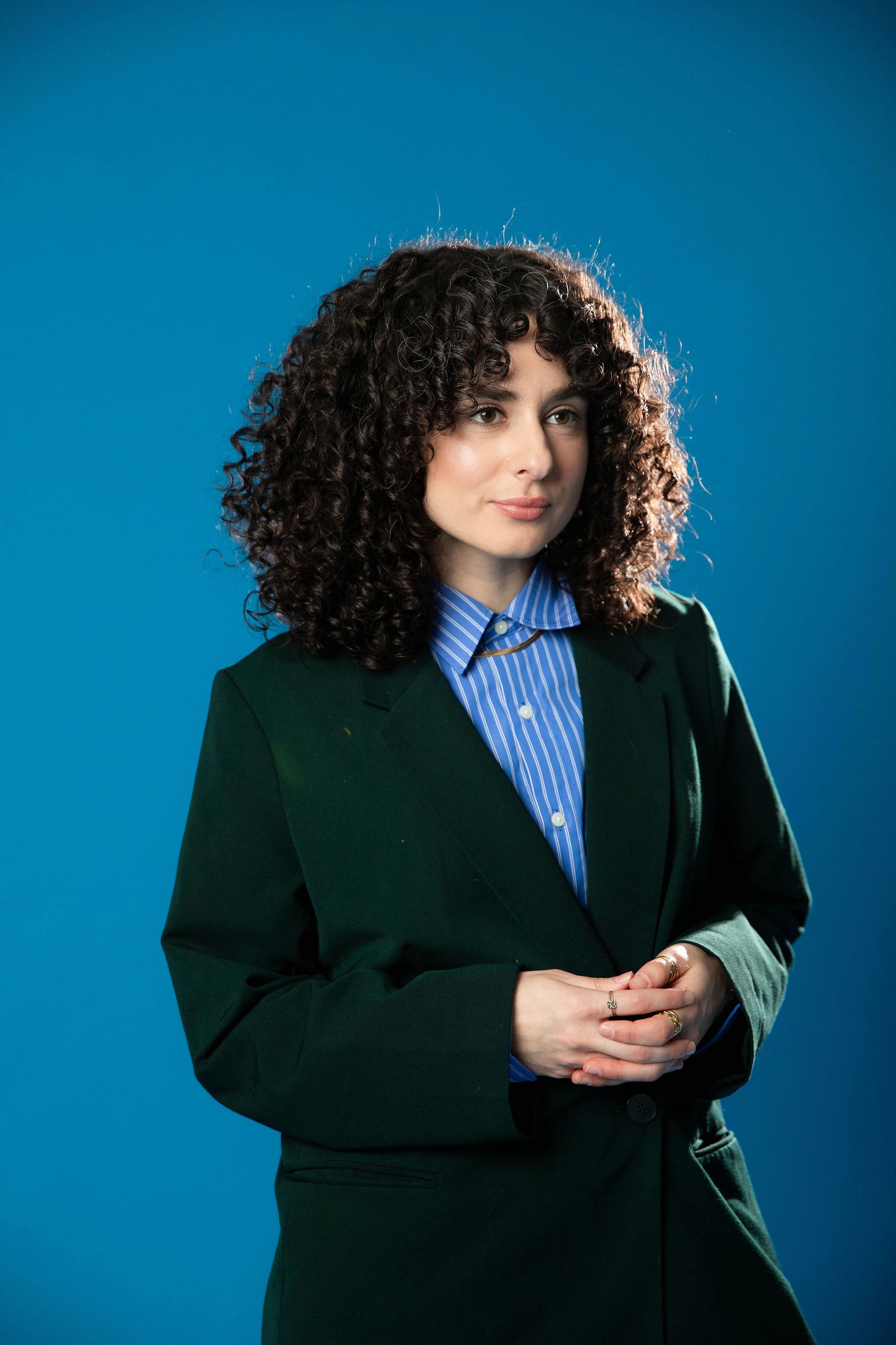A thoughtful young person with dark hair gazes to the side, captured in soft black and white lighting.