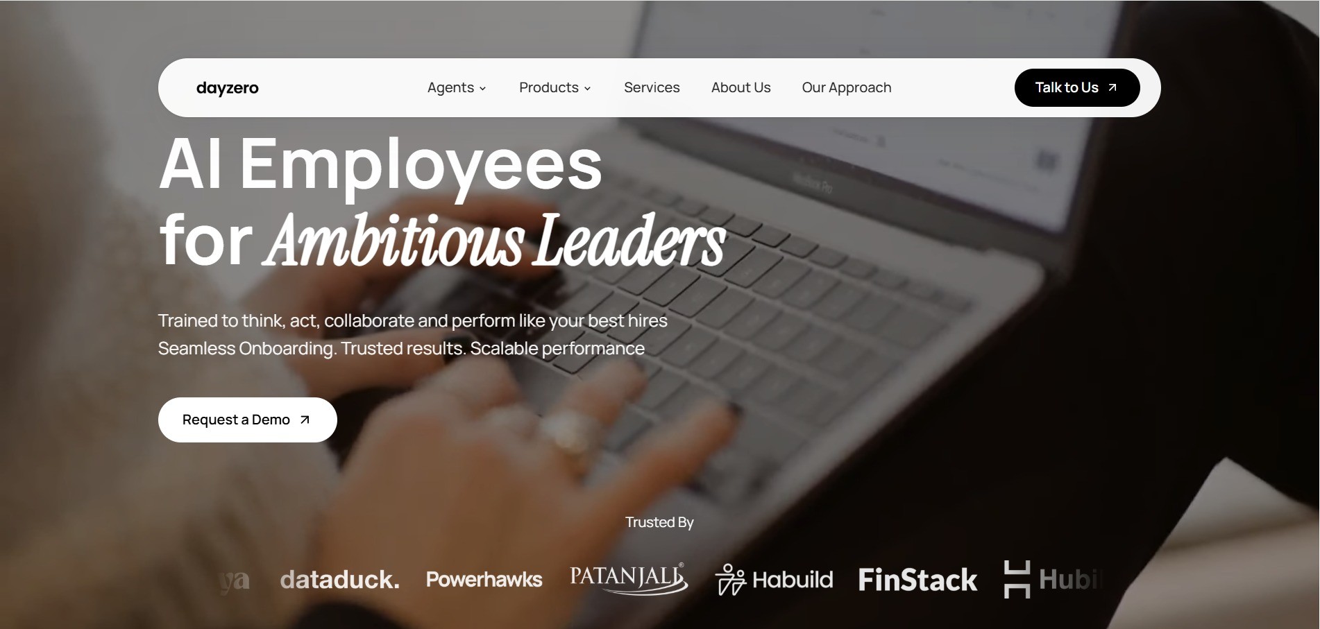 Dayzero.ai homepage hero: 'AI Employees for Ambitious Leaders', a supporting line, a Request a Demo button and a row of client logos over a photo of someone working at a laptop