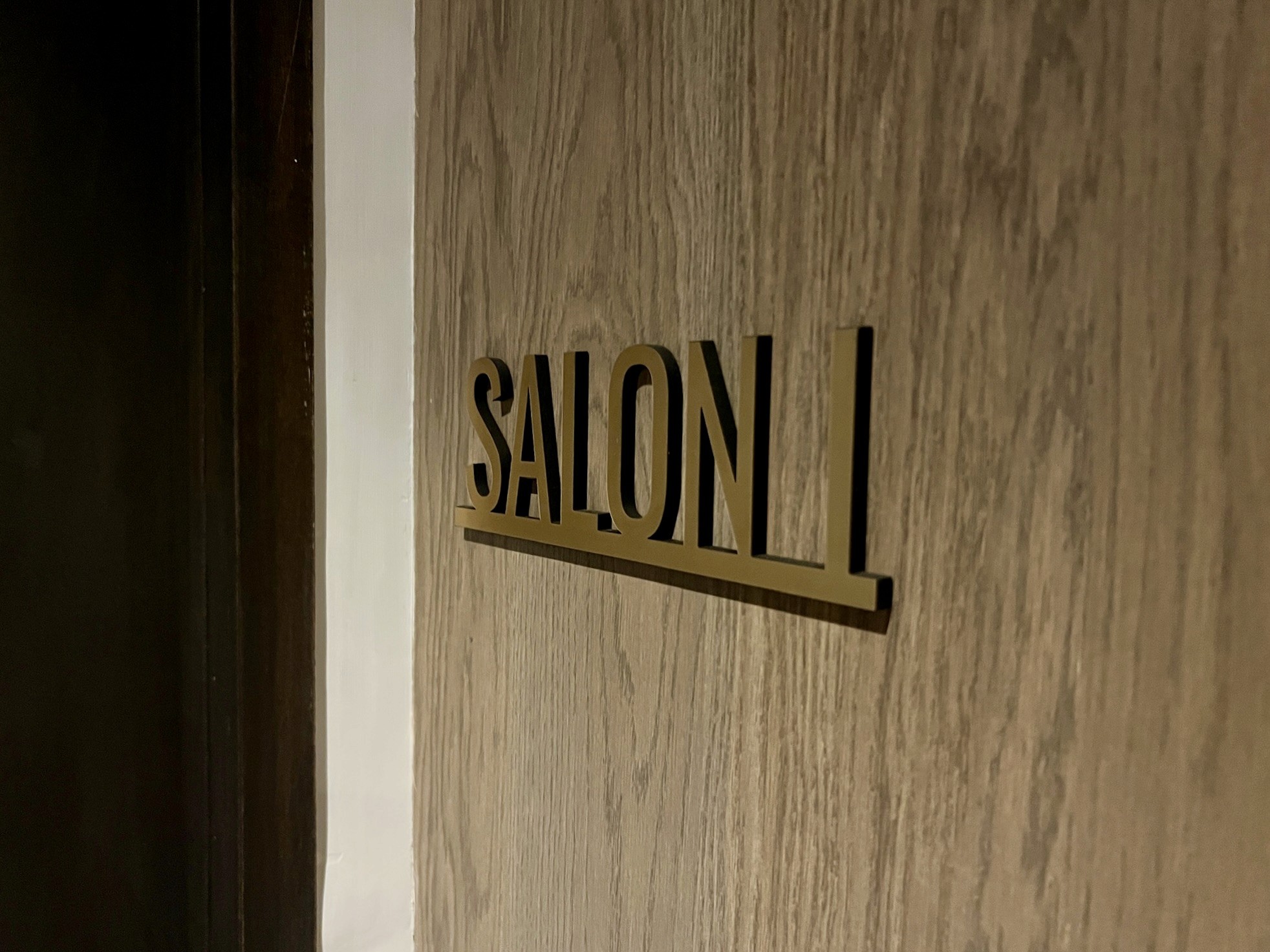 A wooden door with a sign that reads "SALON 1" in a simple, modern font.