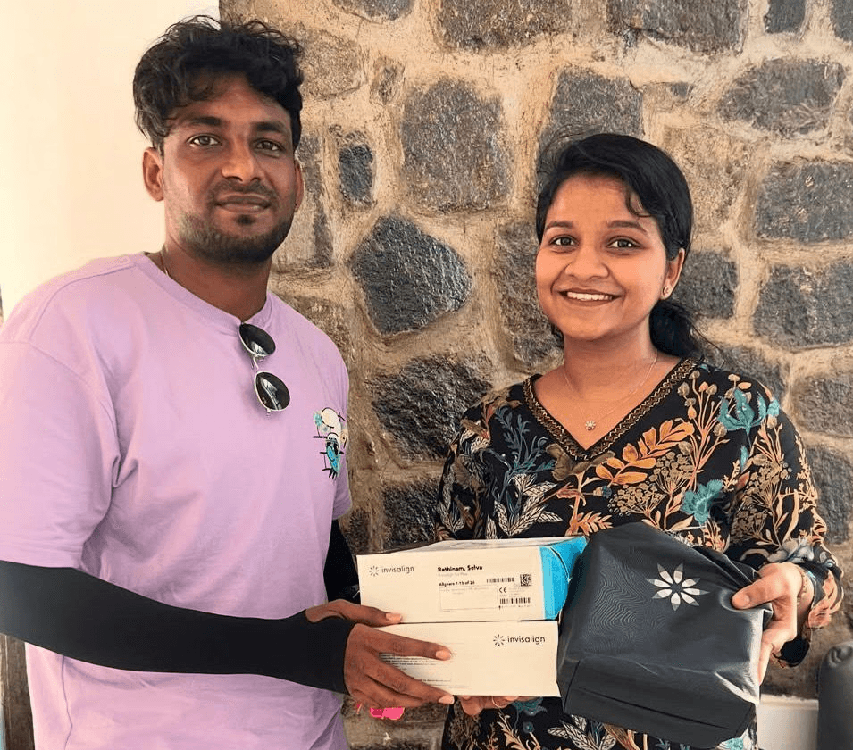 Person with long dark hair holding bouquet of white flowers near face against softly lit background