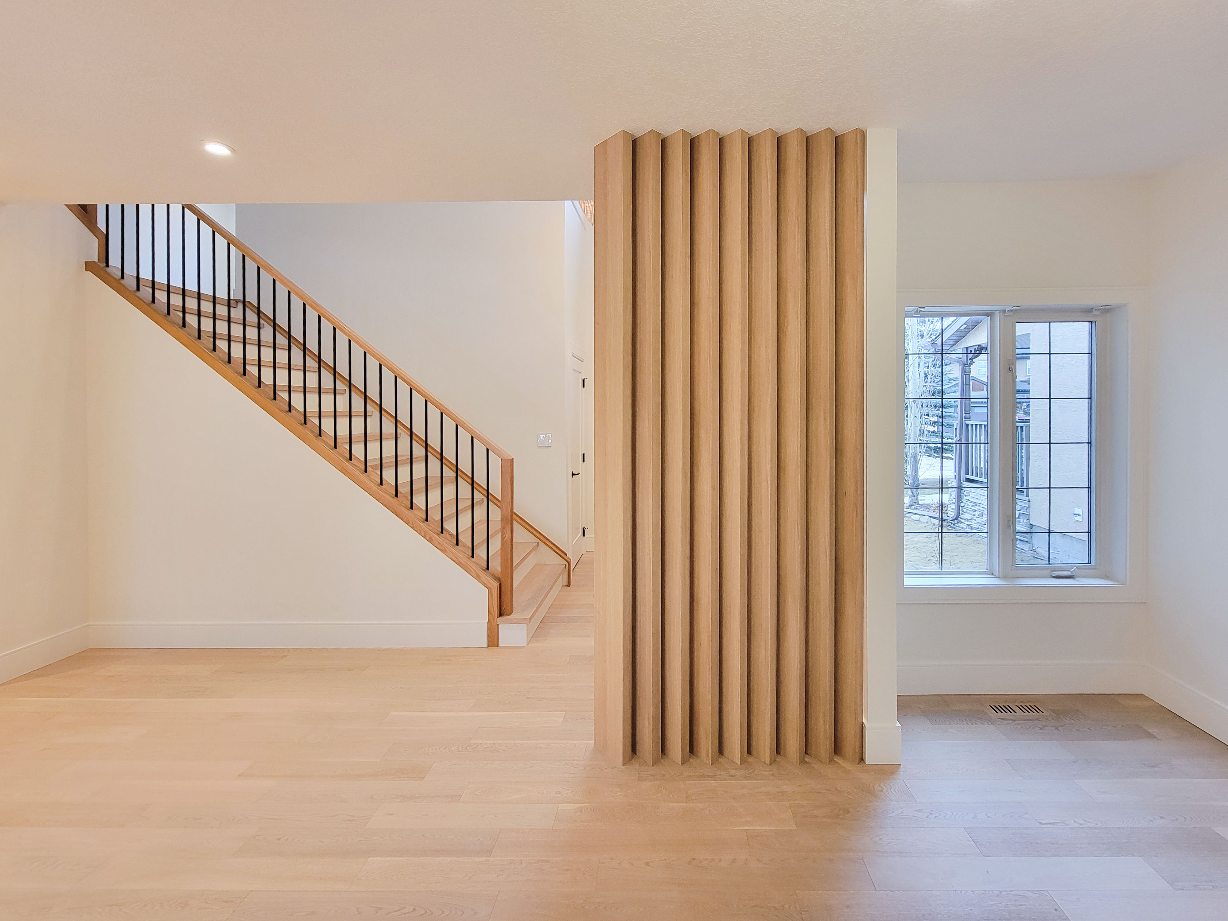 Image of Light wood floor and wall design with staircase and window by KHD Homes interior design team.