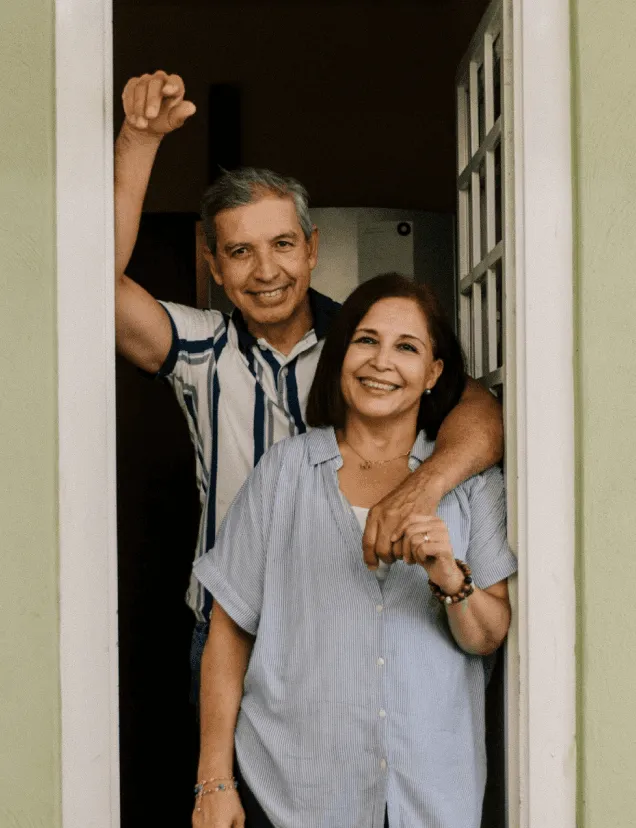 Couple smiling in a doorway, one raising a fist.