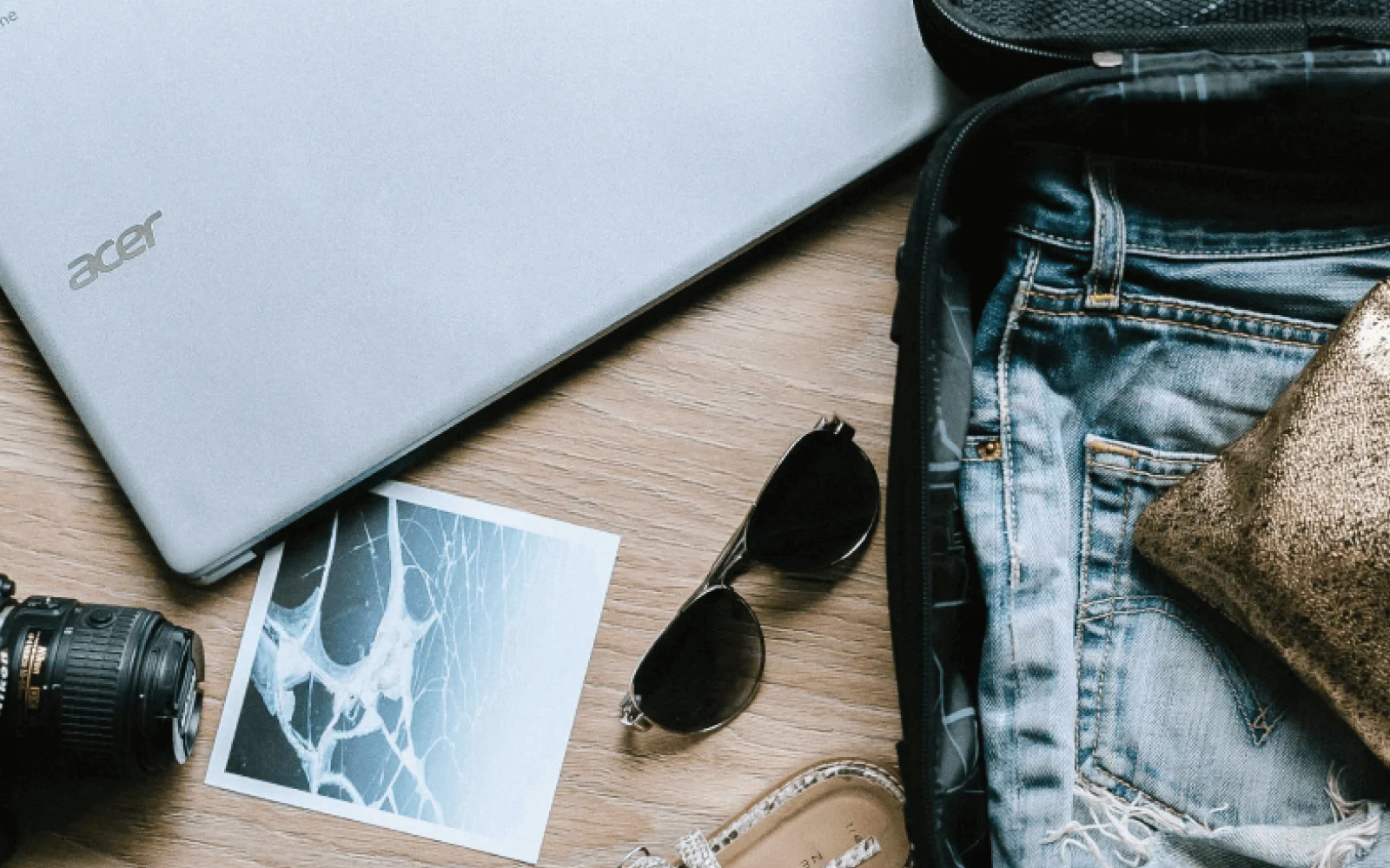 A laptop and camera and women's clothing being packed for a trip to Costa Rica