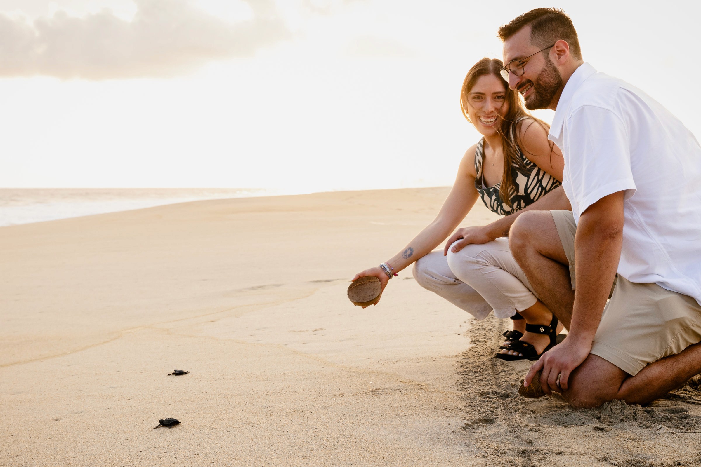 Pareja celebrando su compromiso liberando tortugas frente al mar en Puerto Escondido