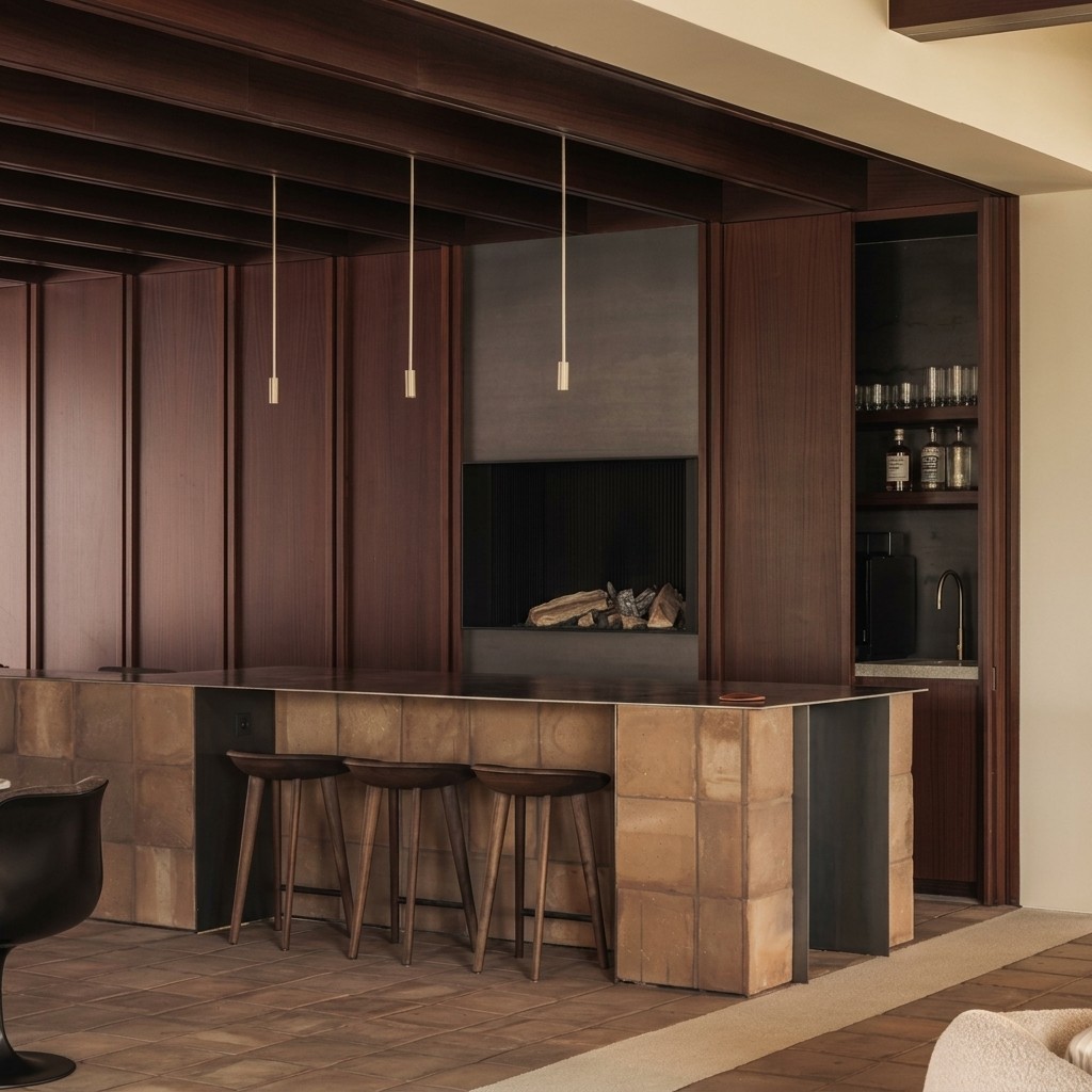 Modern kitchen with dark wood paneling, exposed ceiling beams, and a distinct island clad in warm terracotta tiles.