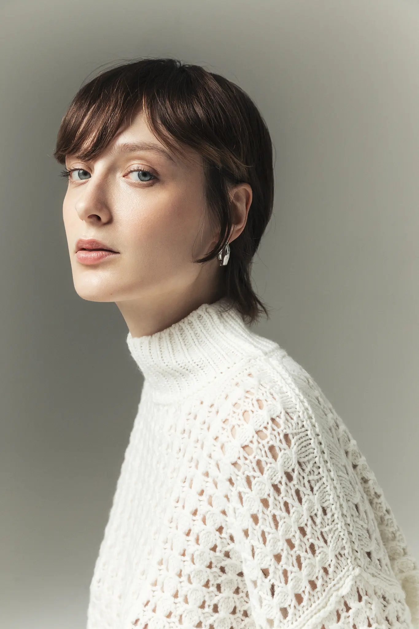 Close-up of woman in white open-knit cashmere turtleneck – Aida Barni Italian knitwear.