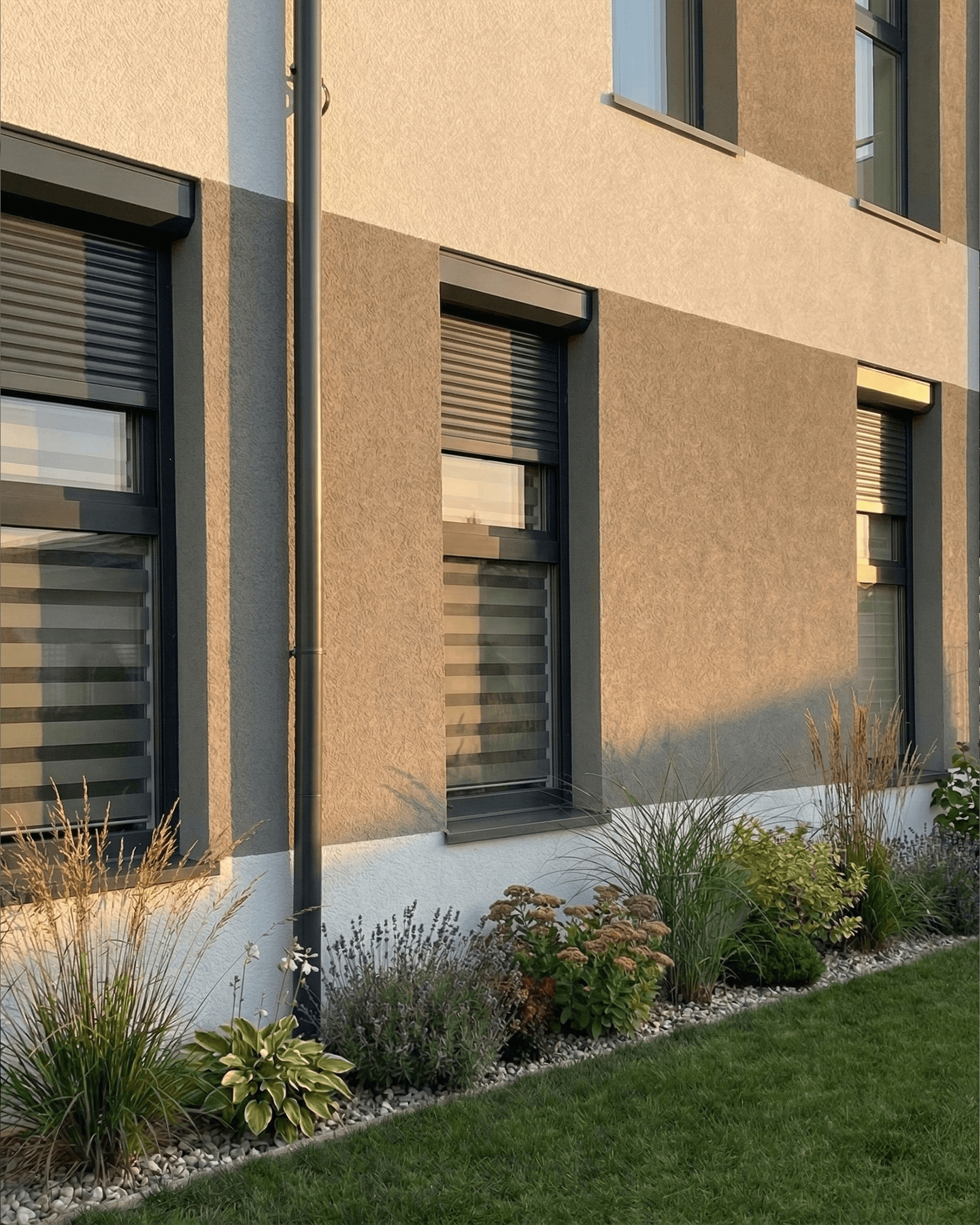 Antracytowe rolety zewnętrzne zamontowane na nowoczesnej elewacji domu jednorodzinnego. Profesjonalne systemy zabezpieczeń okiennych HeyShade – realizacja w Pruszkowie.