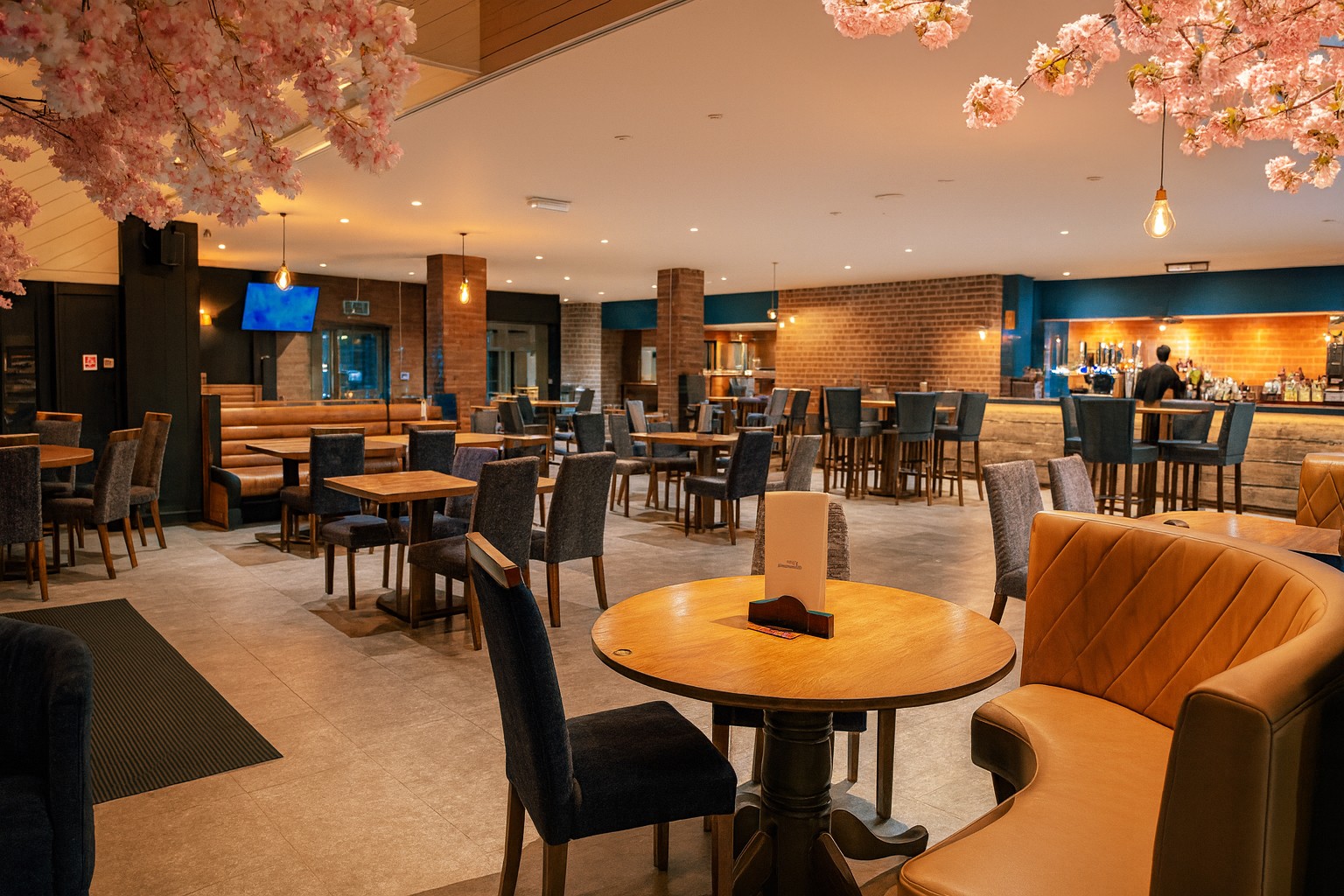 Bar interior with tables in foreground and bar to rear