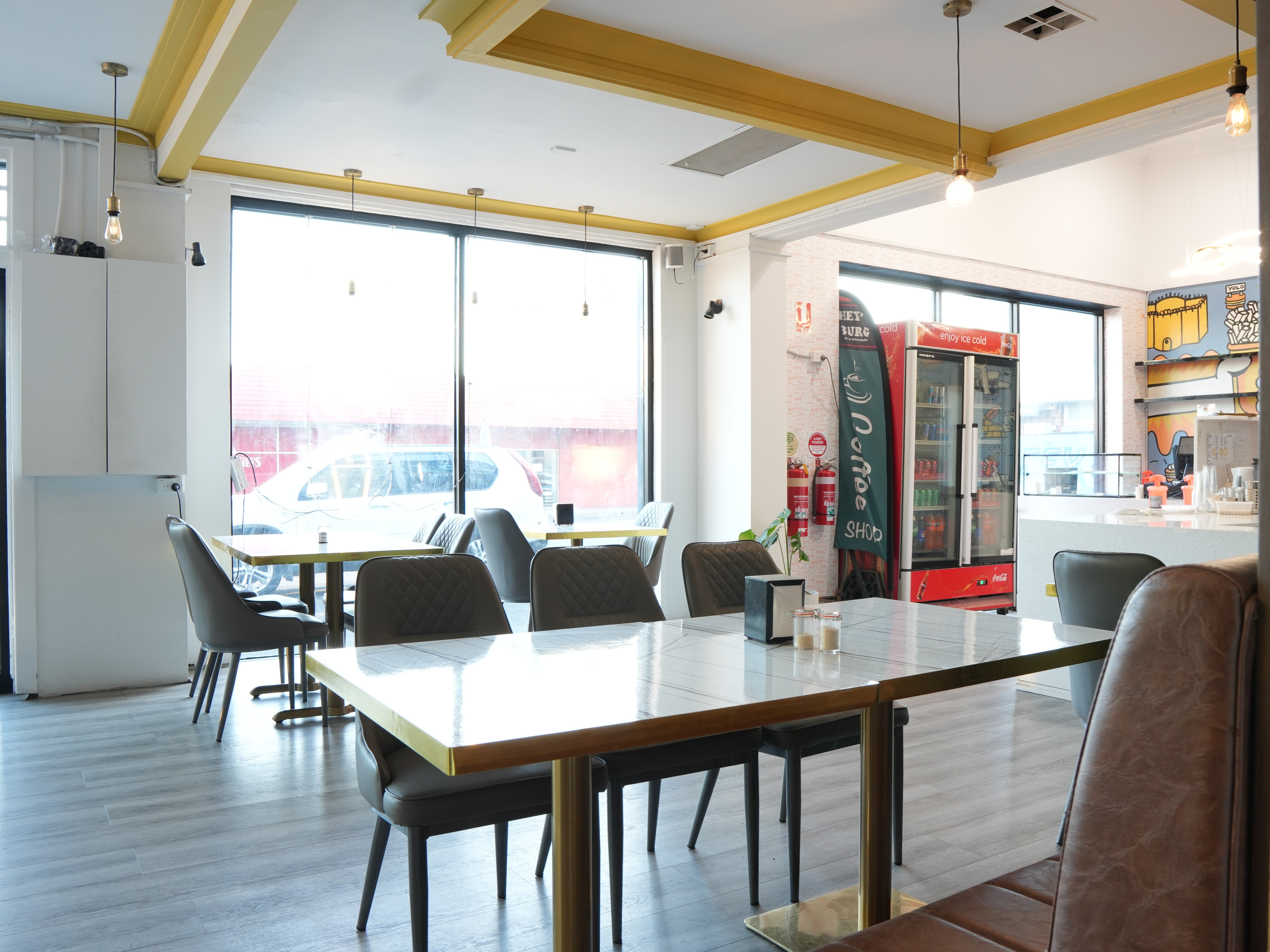 Hospitality fit-out for Heyburg in Coburg, Victoria with neon Hey'Burg signage, terrazzo counter, custom pop-art murals, brass pedestal tables, pendant lighting.