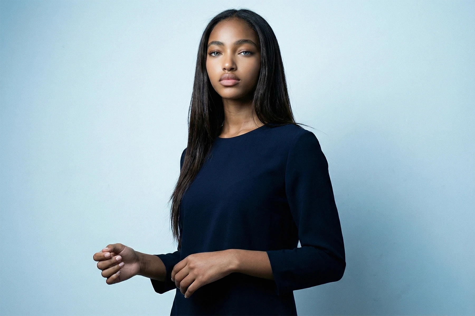 Selbstbewusste Frau im dunkelblauen Kleid vor hellem Hintergrund als Symbol für einzigartige Positionierung durch unsere Branding Agentur Köln.