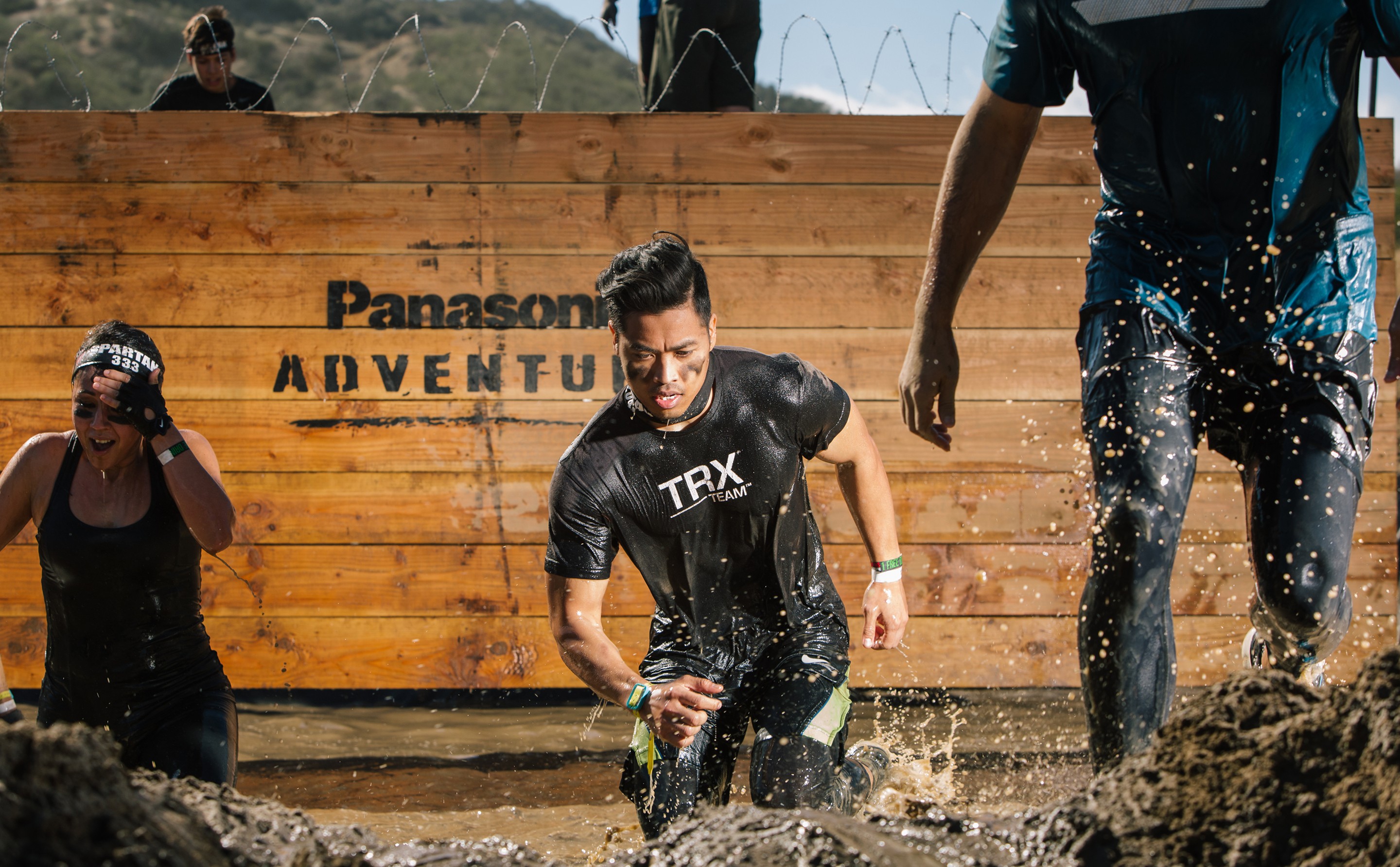HIgh contrast photo of Spartan racers running through water after a wall climb obstacle