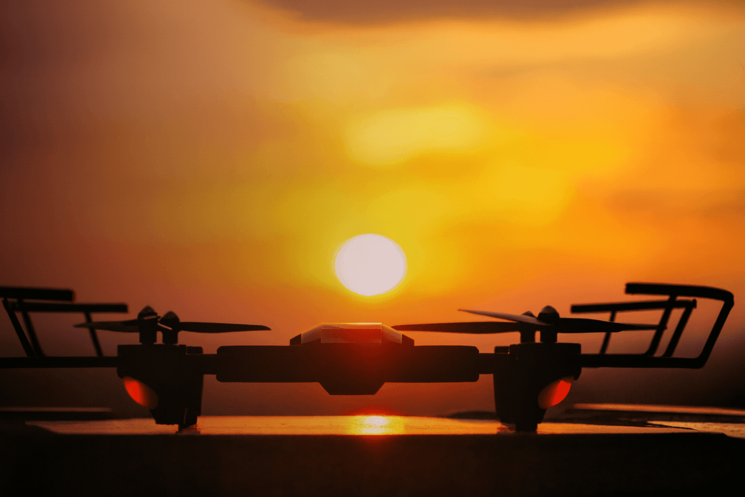 Silhouette of a drone against a bright orange sunset sky, symbolizing drone regulations in India.