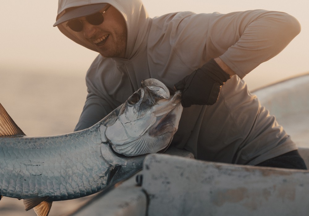 Angler lifting tarpon to boat after catch in southern Belize