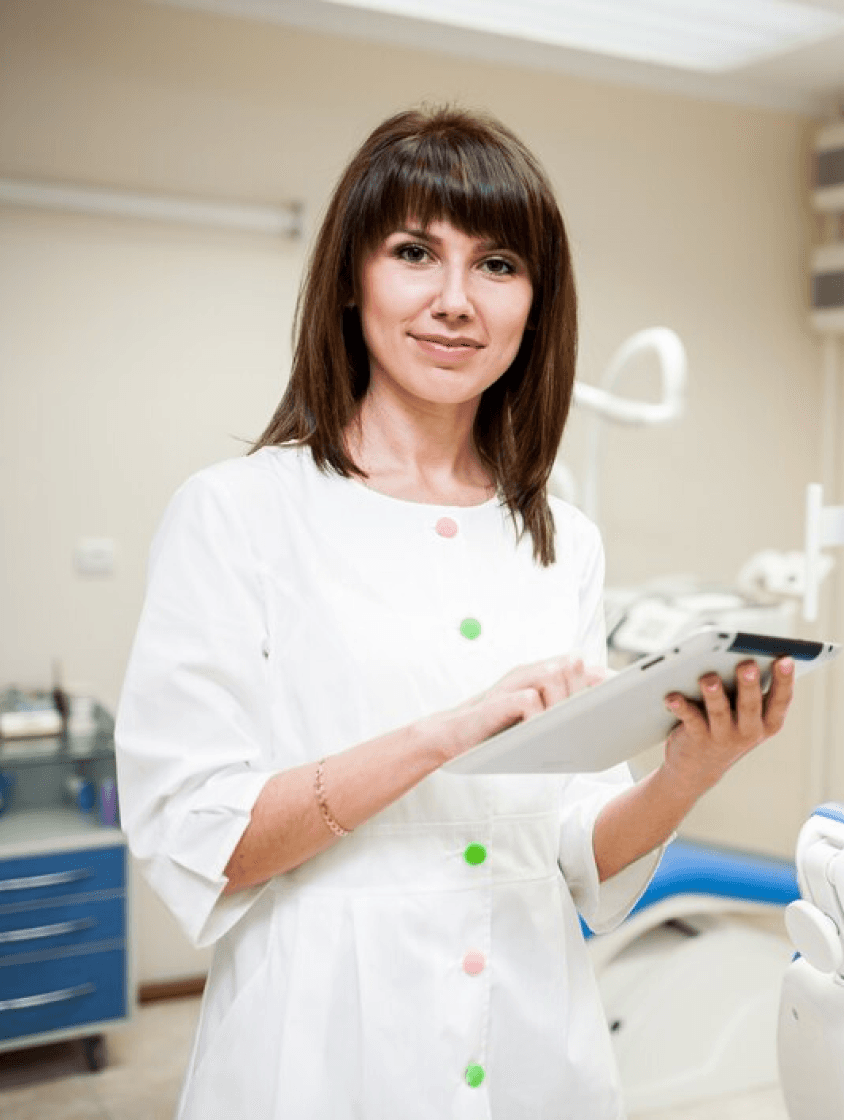 A female dentist holding a dental model, explaining the filling and sealing process to a patient.