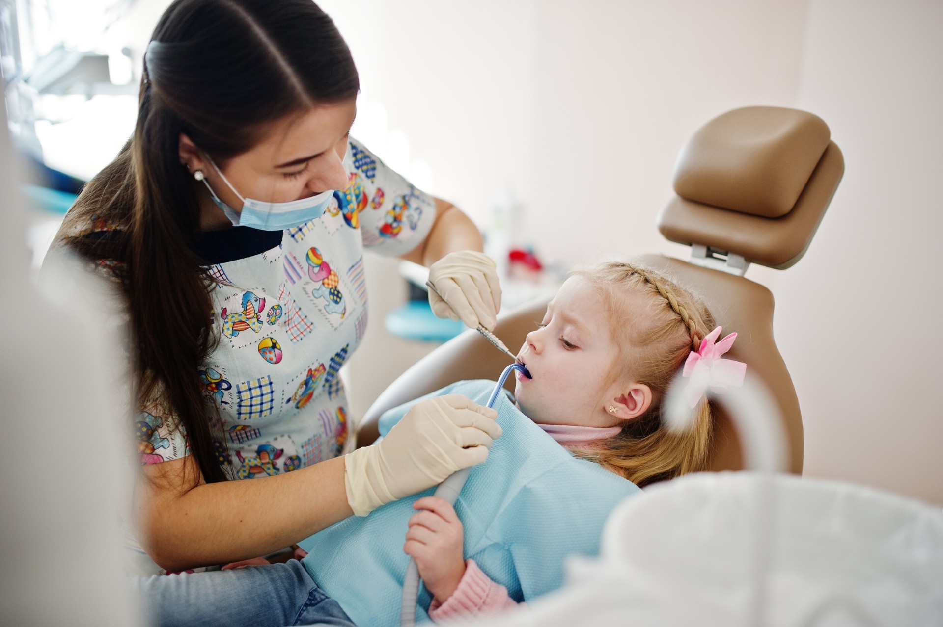 Dentist performing a dental check-up on a young girl in a pediatric dental clinic.