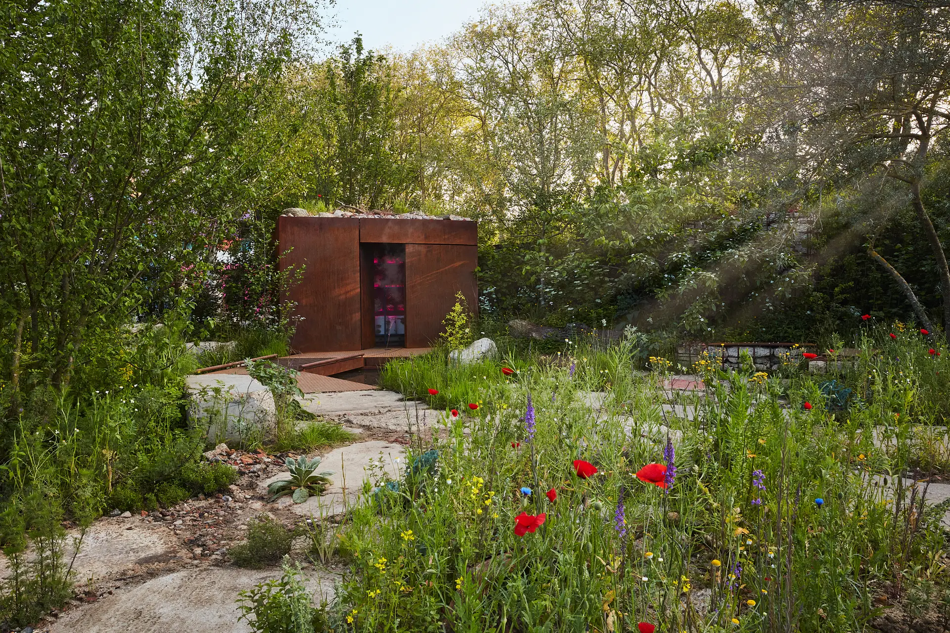 A serene garden pathway leads to a rustic wooden shed, surrounded by lush greenery and colorful blooming flowers.