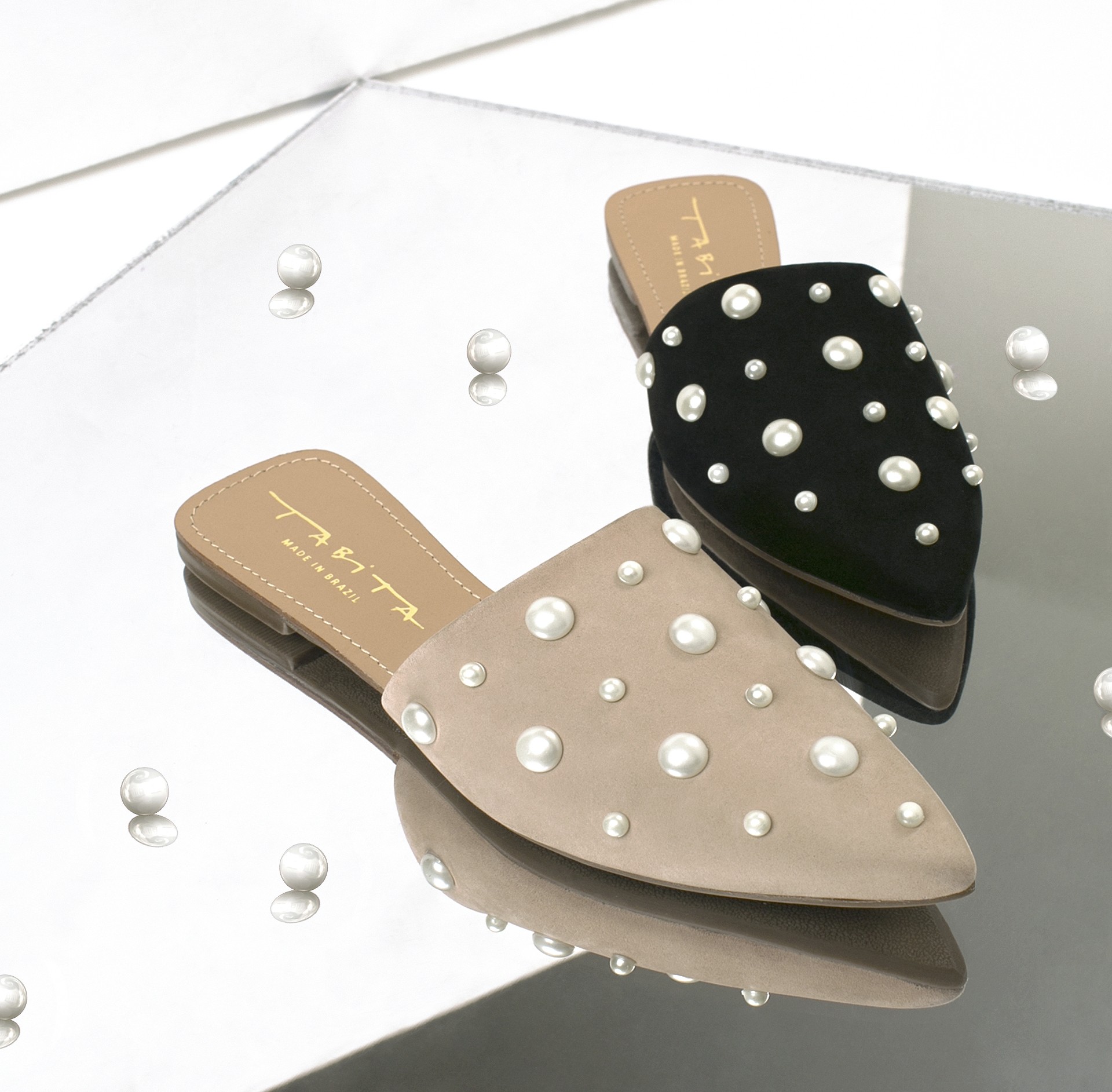 Tabita sandals from La Favorita Shoes, adorned with pearls, displayed on a mirrored surface reflecting pearls around.