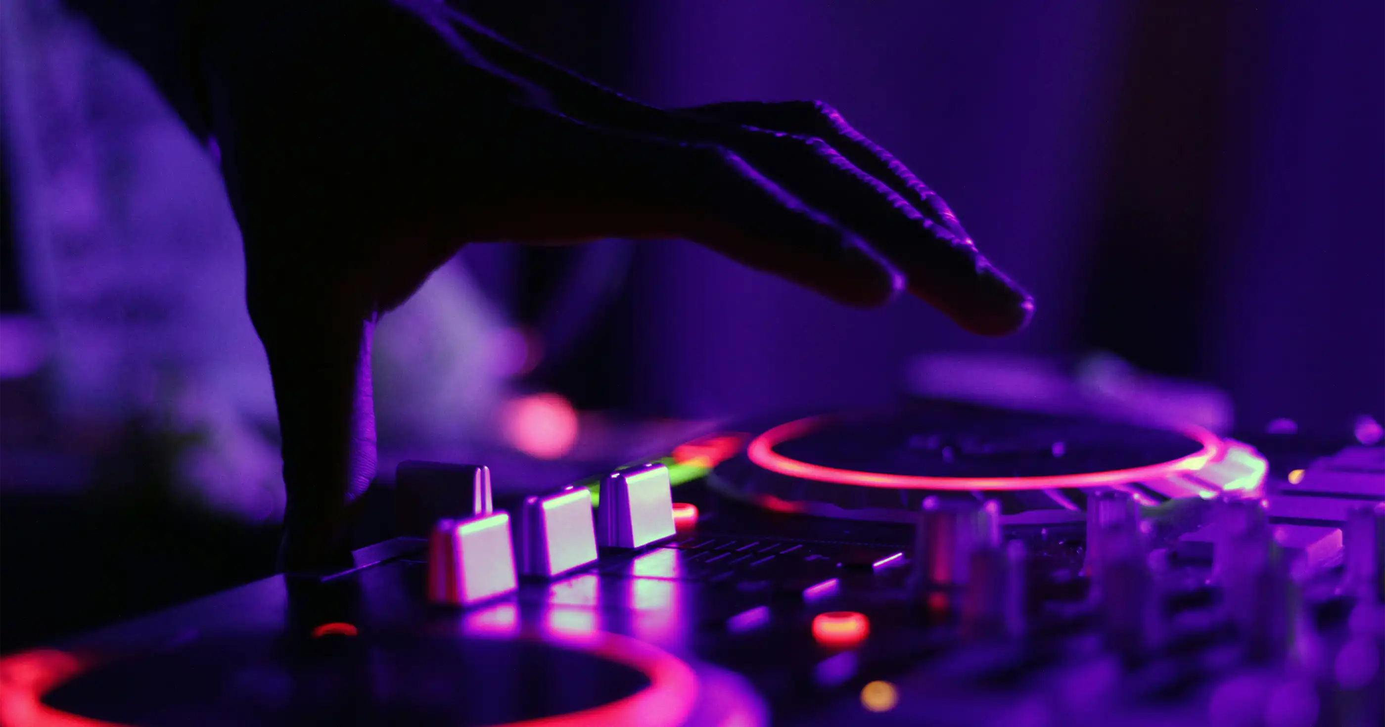 a hand hovers over a dj mixing board