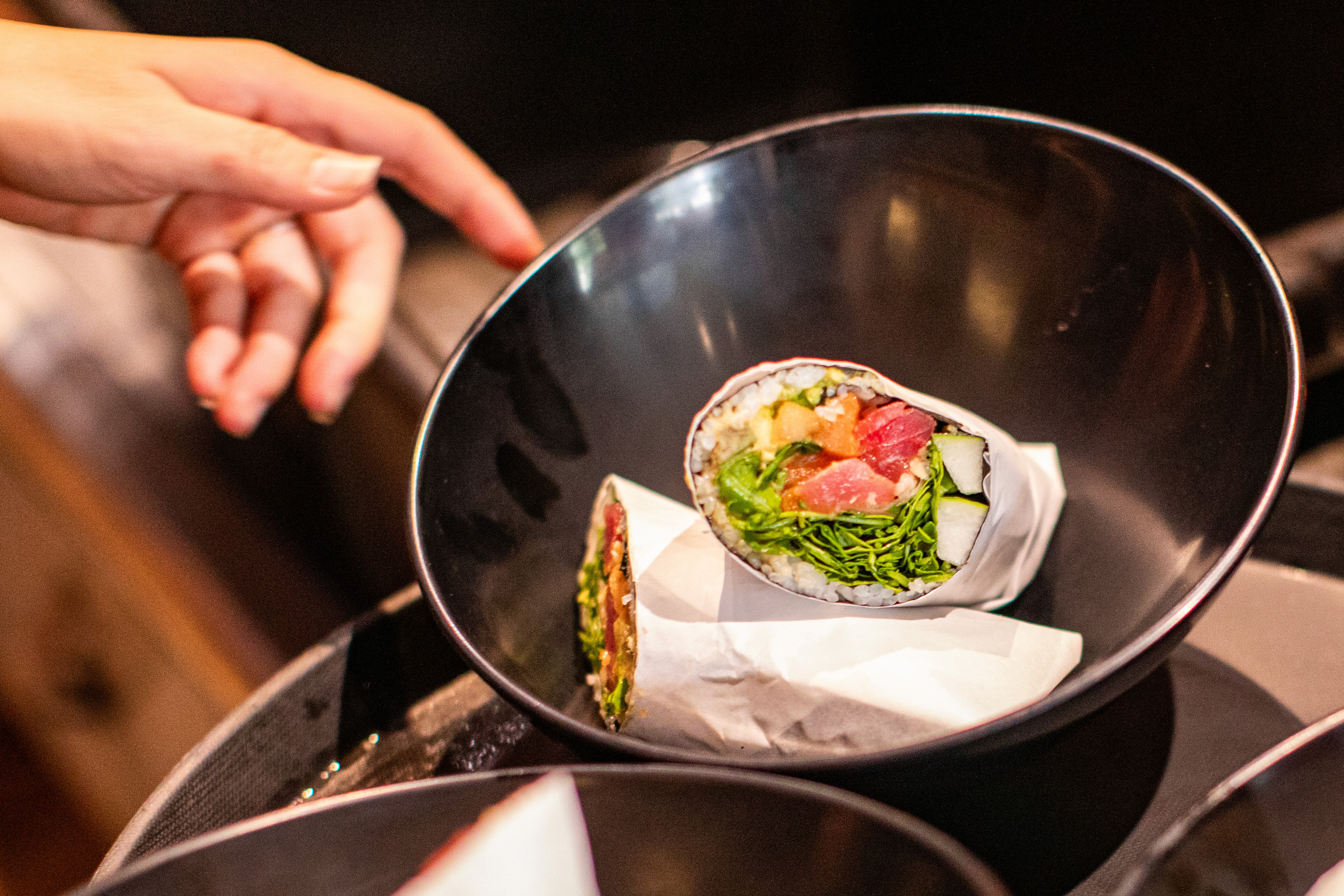 A gourmet plate featuring a golden-brown, breaded chicken cordon bleu or roulade, sliced to reveal a yellow filling, served with a creamy sauce, roasted potato wedges, and a side of fresh salad greens on a wooden table.