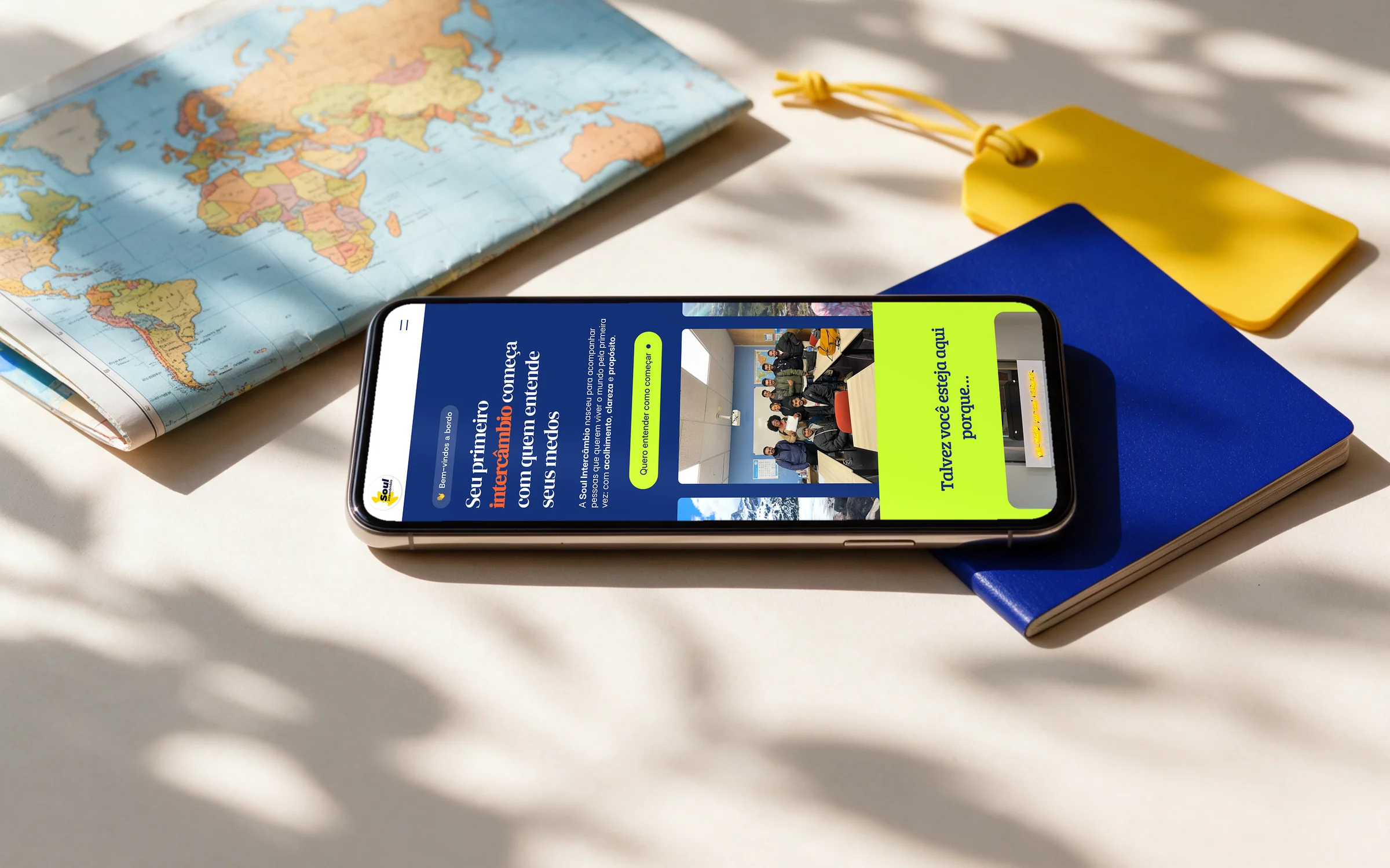 Página inicial do site da Soul Intercâmbio num celular, ao lado de um passaporte e de um mapa